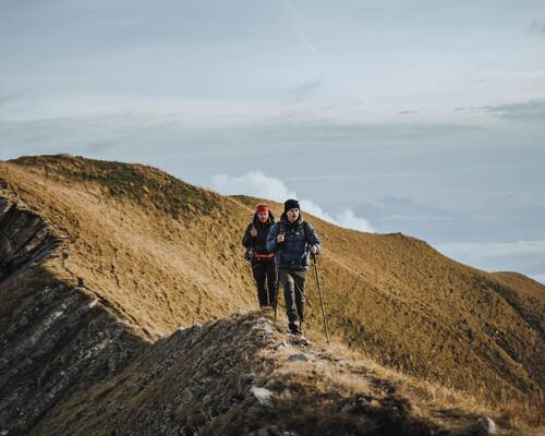 kobieta i mężczyzna wędrujący po górach w odzieży trekkingowej z kijami trekkingowymi w rękach