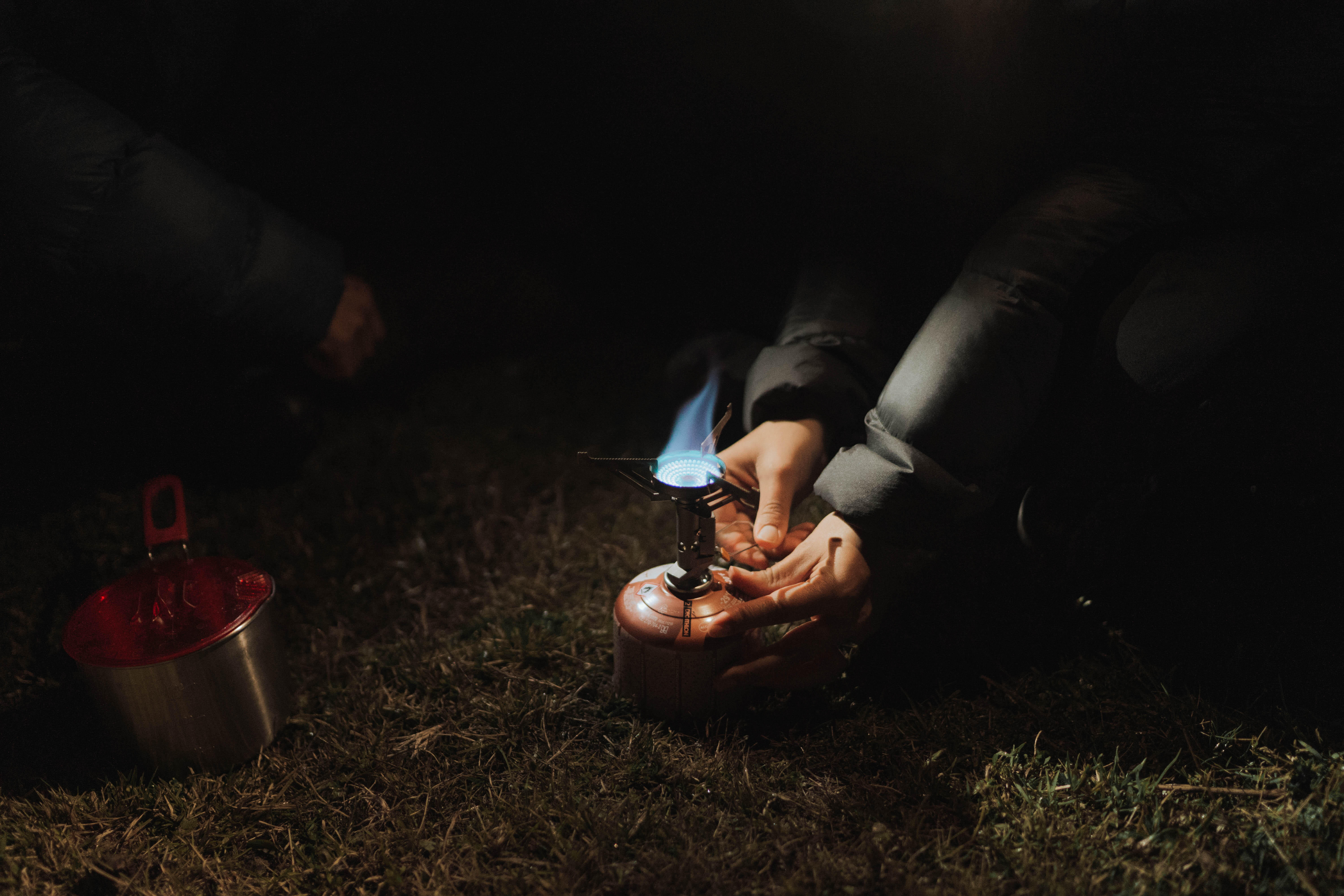 Butane gas canister attached to a portable camping stove at night