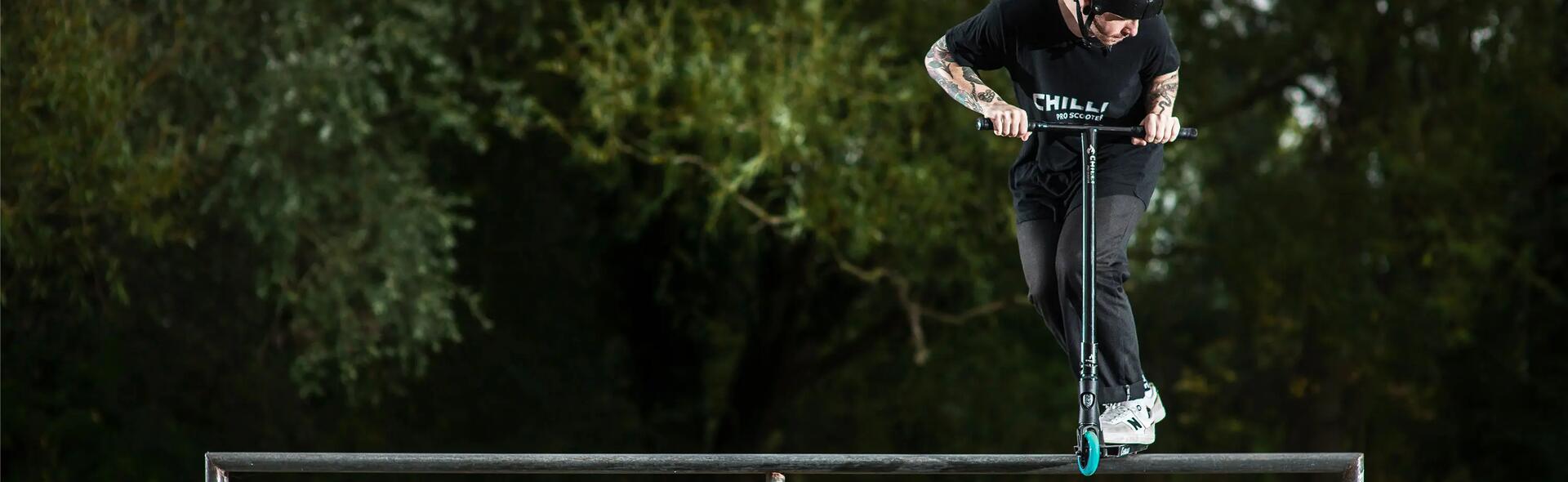 A man grinding on a rail with a stunt scooter