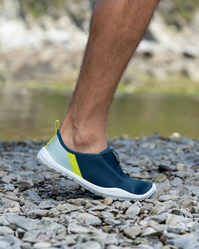 Man met Aquashoes aan loopt over kiezels