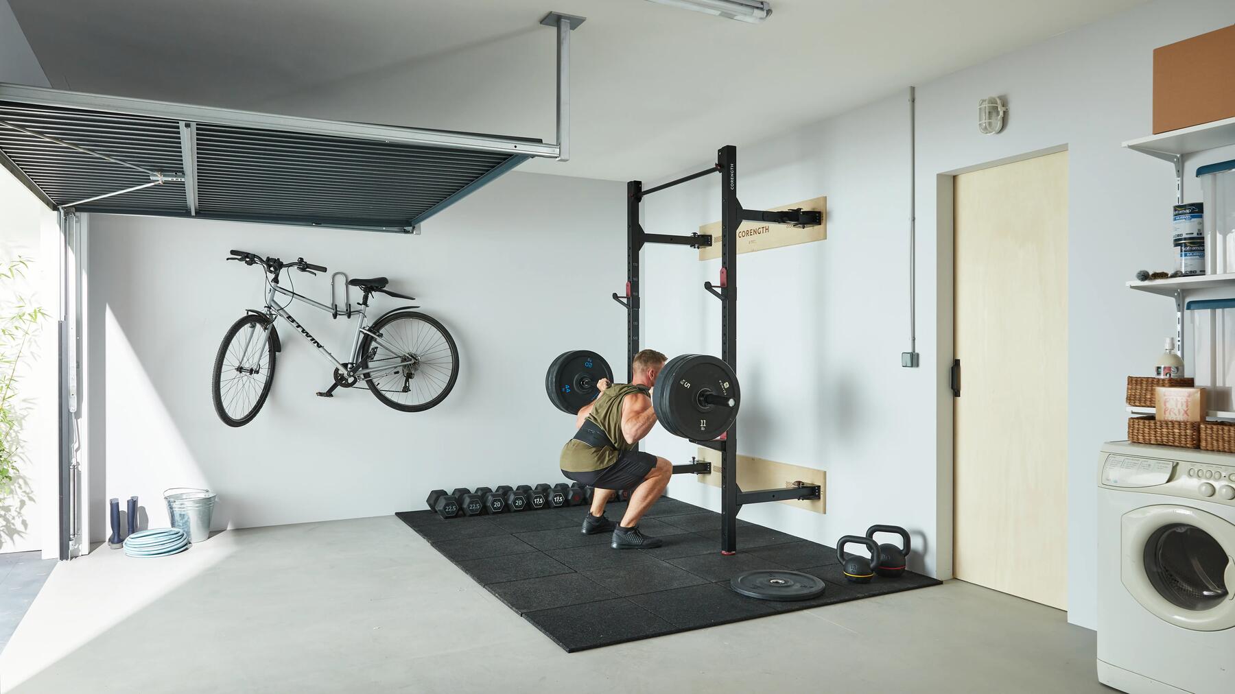 Man die squat met veel gewichten in zijn garage