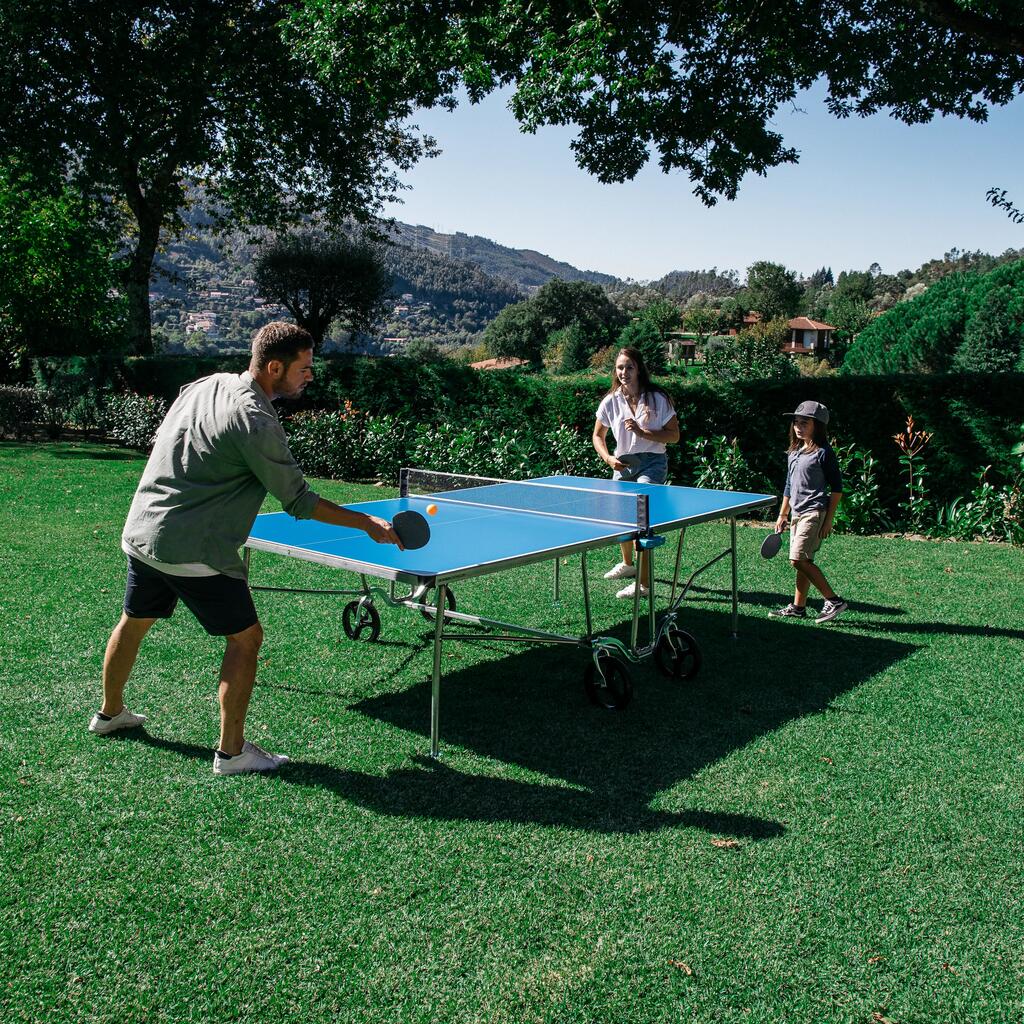 Družina igra namizni tenis na vrtu.