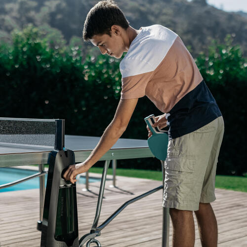 Prise en main d'une balle de tennis de table dans le porte-balles et raquettes présent sur la table de ping pong extérieure PPT 900 OUTDOOR .2