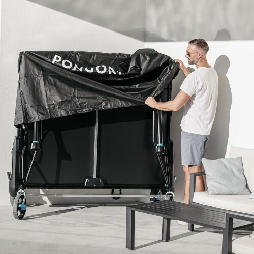 Bir kişi PPT930 OUTDOOR .2 masa tenisi masasıyla birlikte gelen kılıfı takıyor