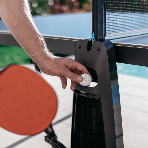 Prise en main d'une balle de tennis de table dans le porte-balles et raquettes présent sur la table de ping pong extérieure PPT 930 OUTDOOR .2