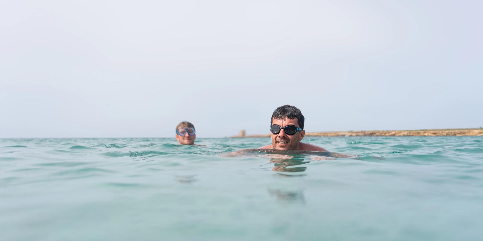 Mężczyźni pływający w otwartym akwenie w okularach do wody