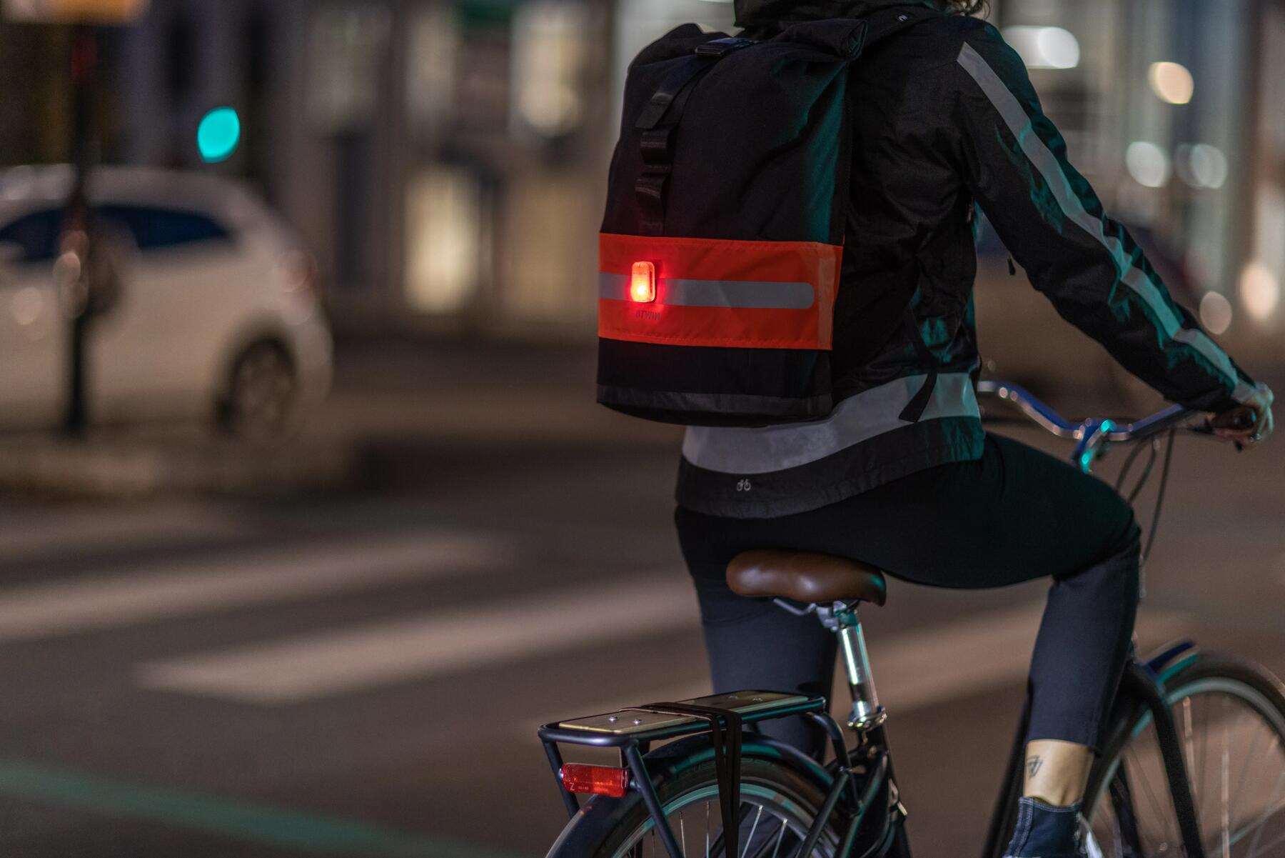 Rowerzysta jadący nocą rowerem z oświetleniem tylnym roweru i odblaskami