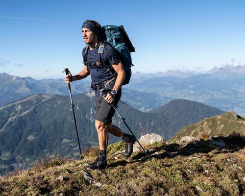 Mężczyzna z kijkami trekkingowymi i z plecakiem wędrujący po górach