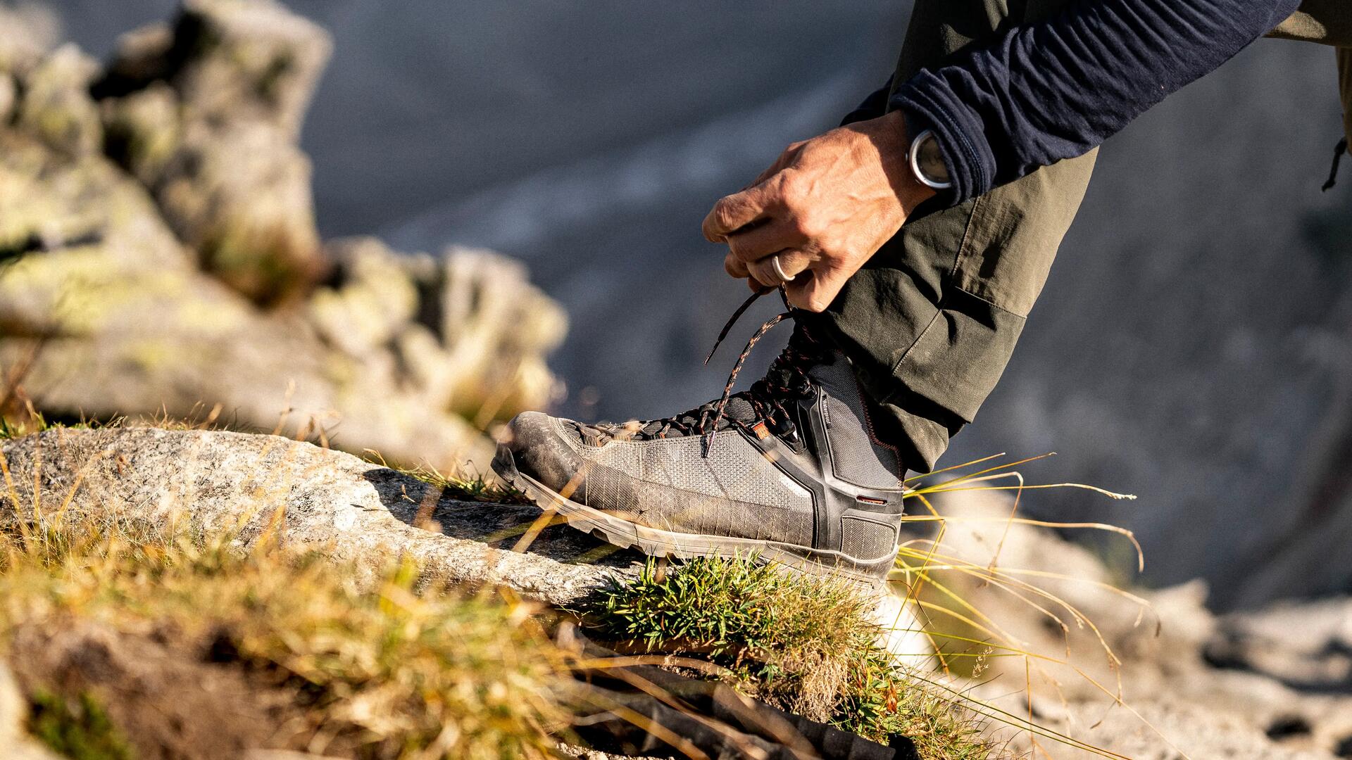 mężczyzna zawiązujący buty trekkingowe w terenie