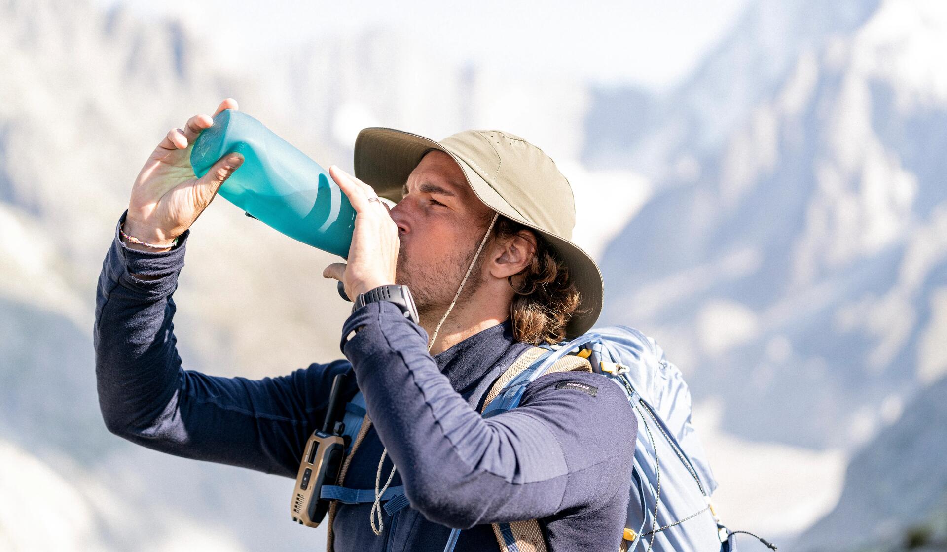 mężczyzna pijący napój z bidonu w górach