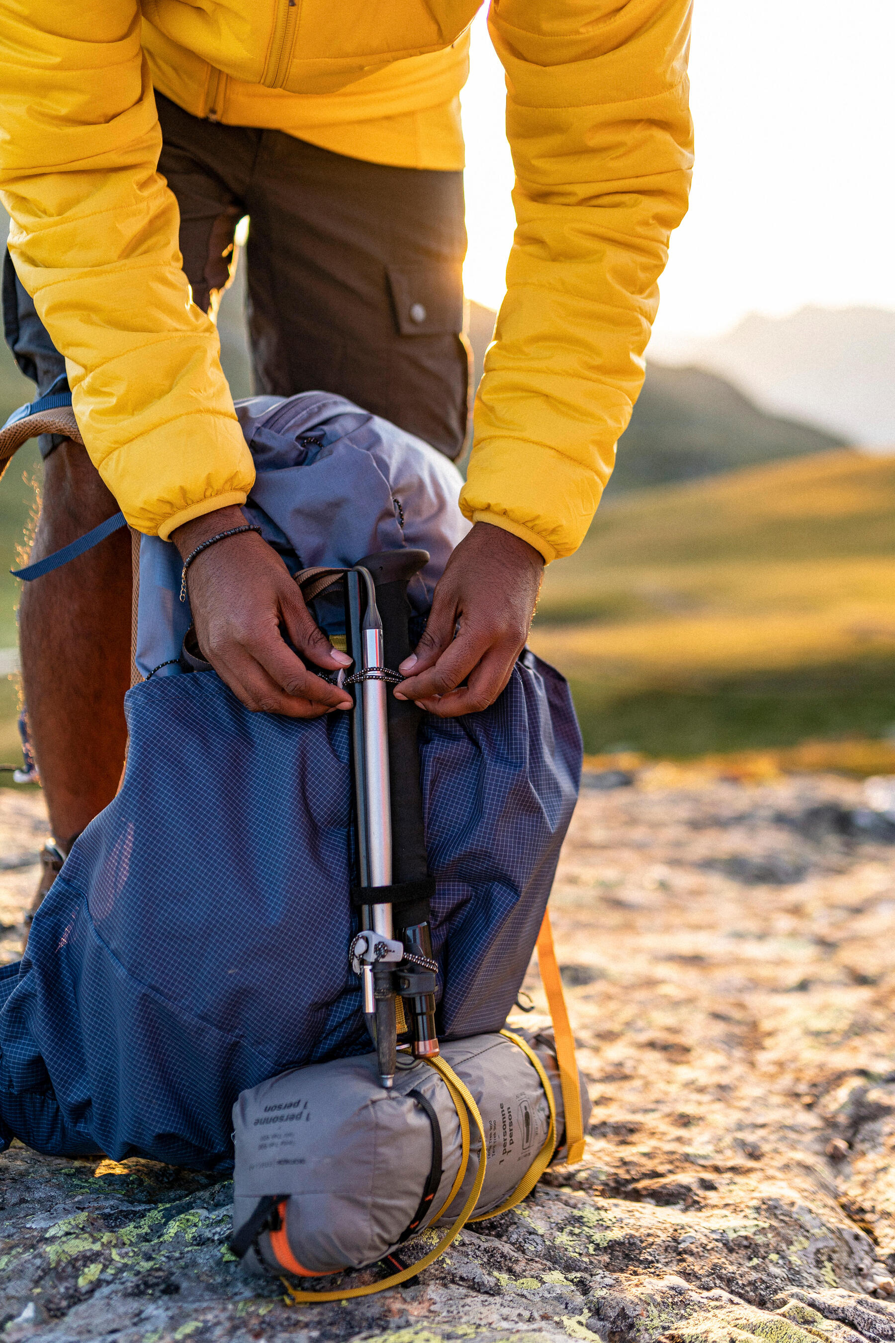 Mężczyzna mocujący kijki trekkingowe do plecaka turystycznego