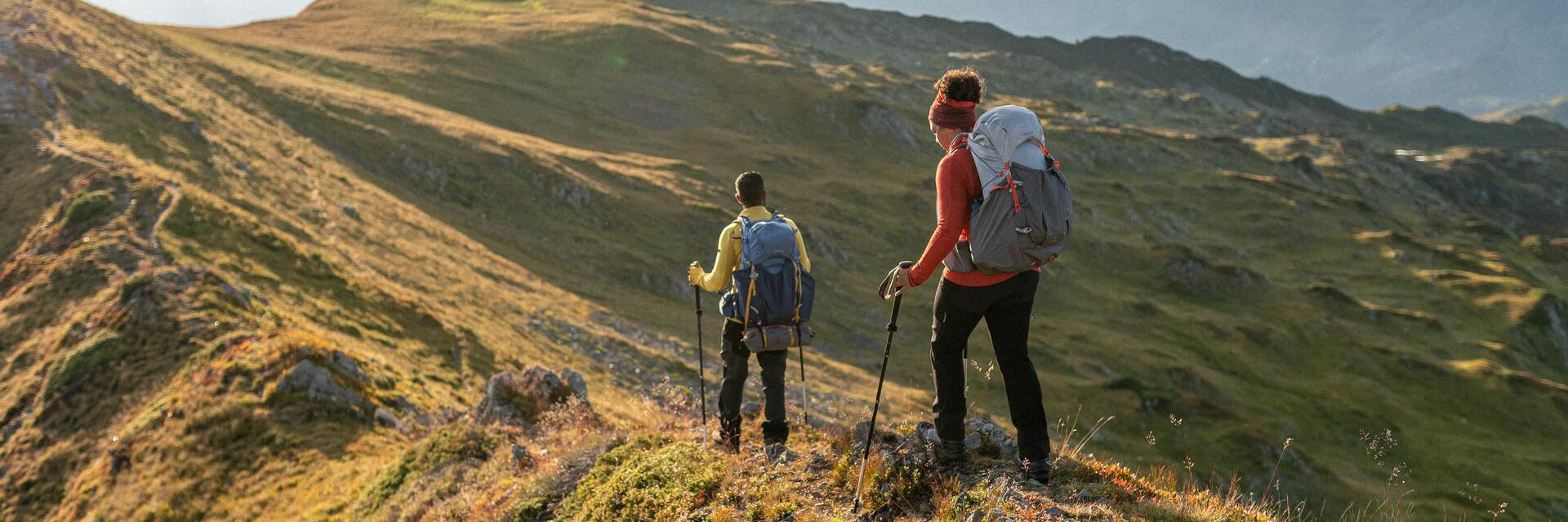 Kobieta i mężczyzna chodzący z kijkami trekkingowymi po górach