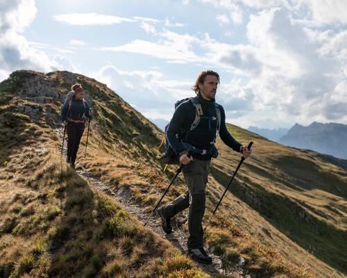 kobieta i mężczyzna wędrujący po górach z plecakami na plecach i kijami trekkingowymi w rękach
