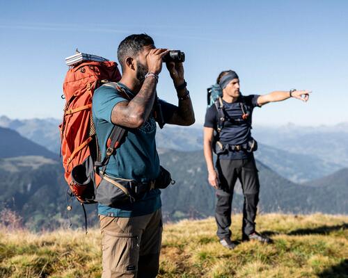 mężczyźni stojący w górach ubrani w odzież turystyczną z plecakami turystycznymi na plecach