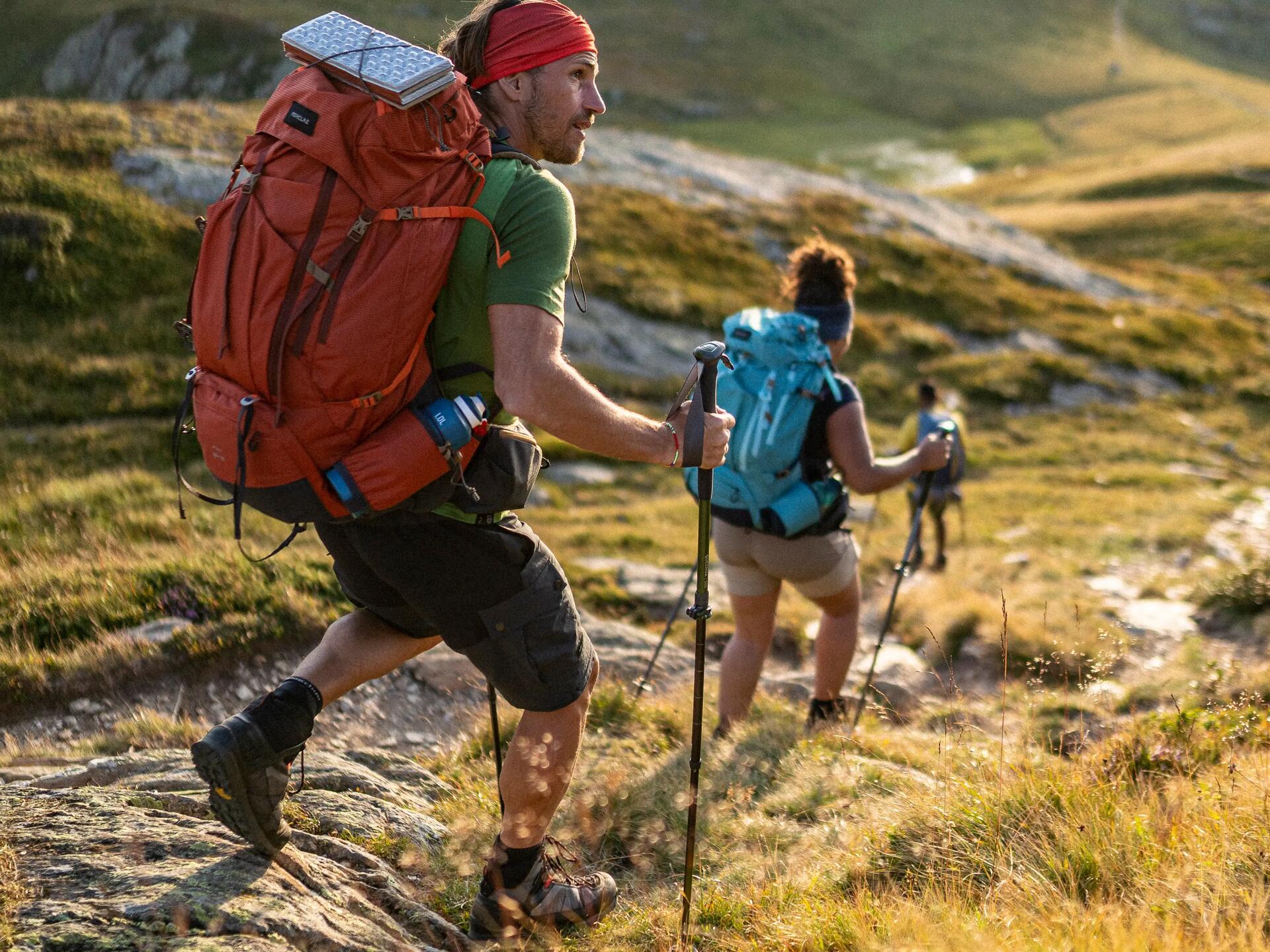 osoby wędrujące po górach w butach i odzieży trekkingowej nosząc plecaki turystyczne na plecach