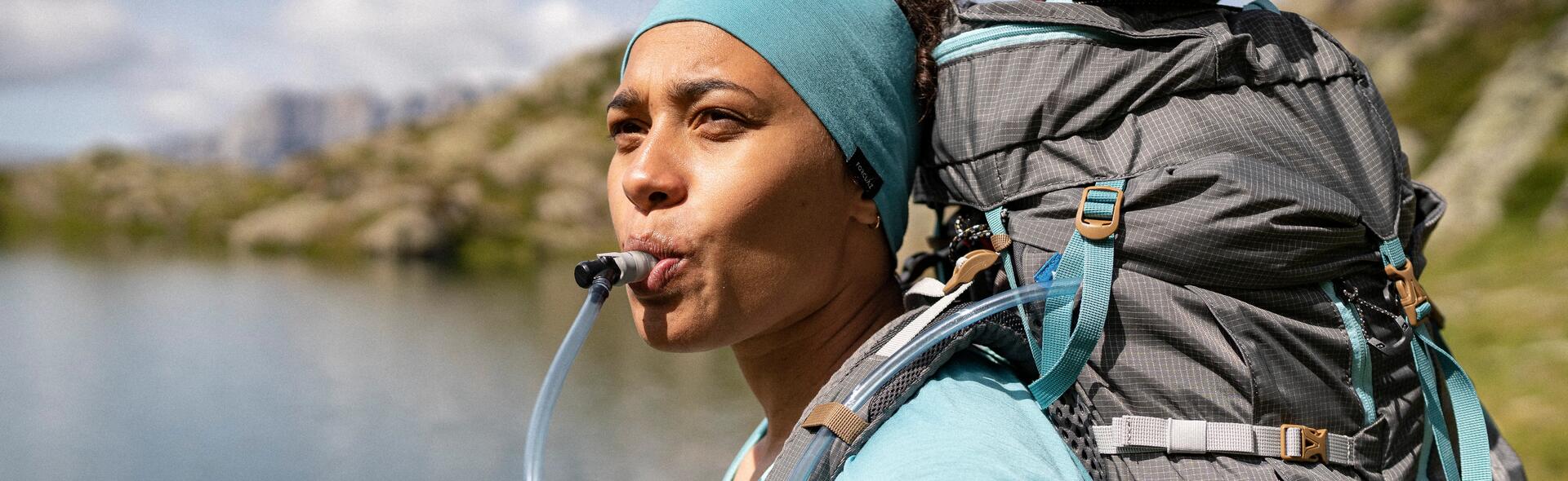 kobieta pijąca wodę z bukłaka schowanego w plecaku turystycznym