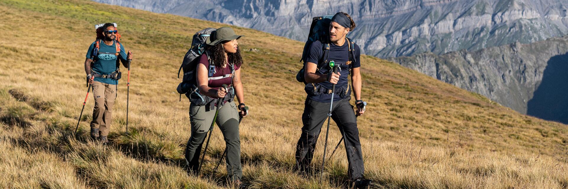 Ludzie z plecakami wędrujący z kijkami trekkingowymi po górach