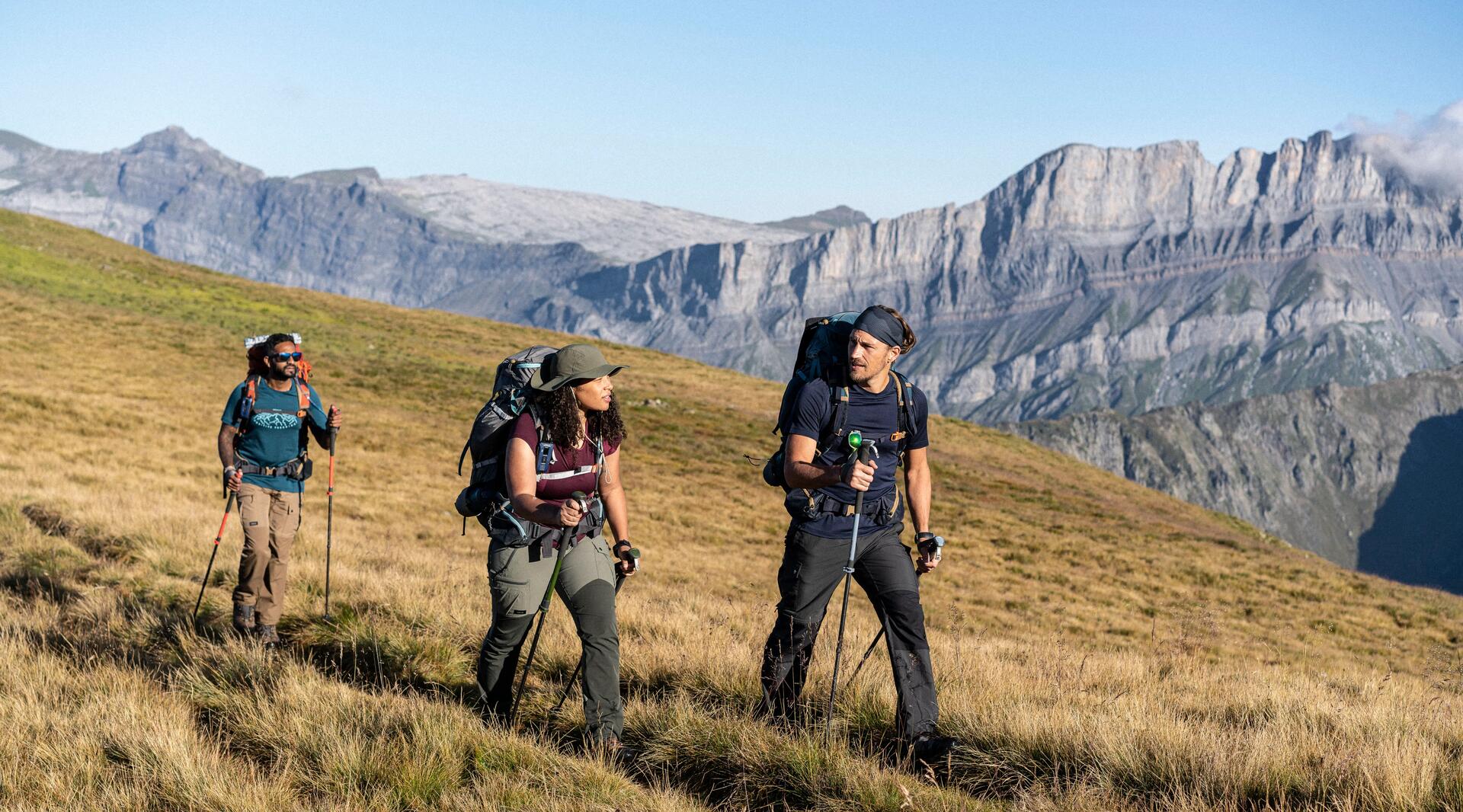Grupa ludzi w strojach trekkingowych z plecakami i kijkami idąca szlakiem
