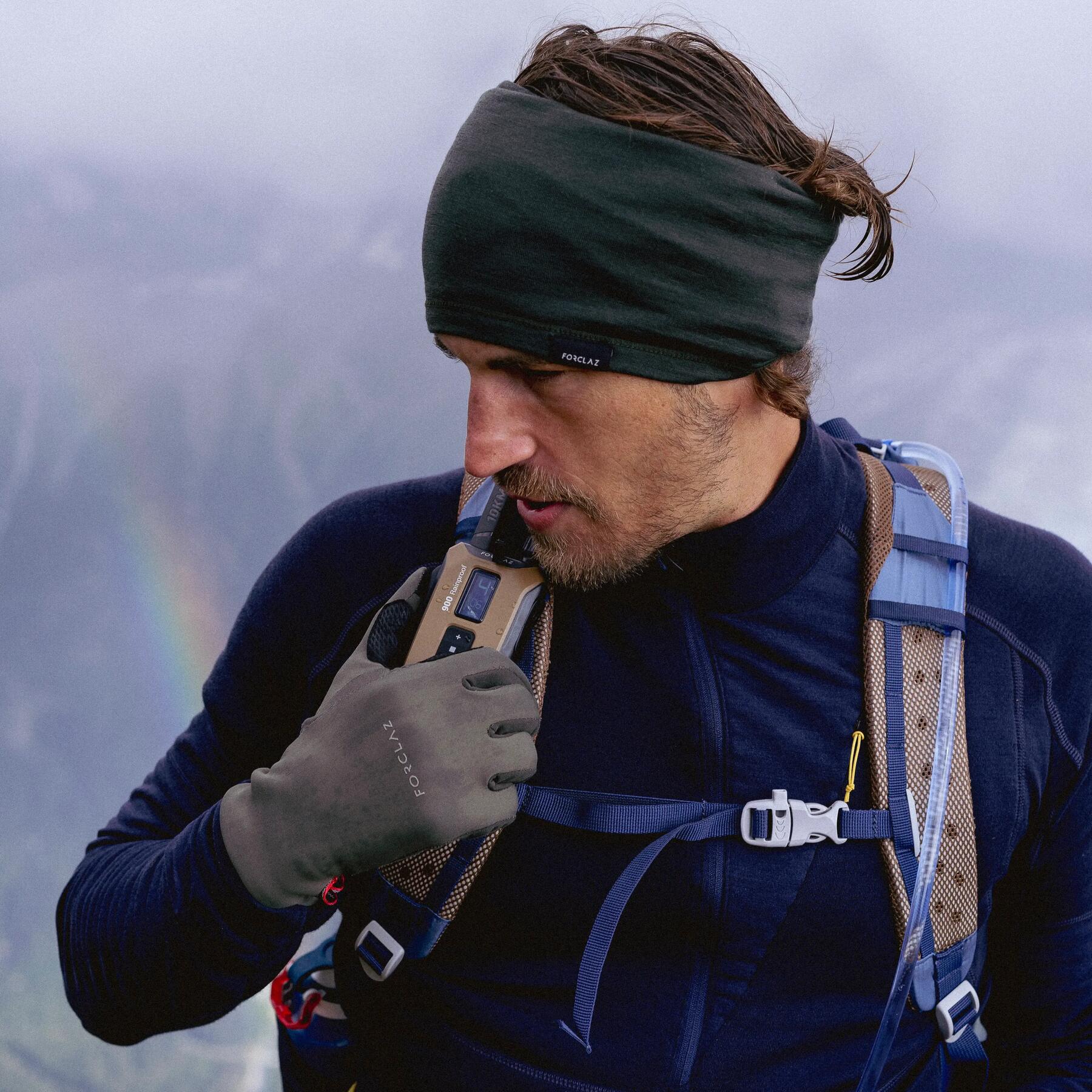 Mężczyzna z plecakiem trekkingowym na plecach sprawdzający pogodę w górach komunikując się przez walkie-talkie