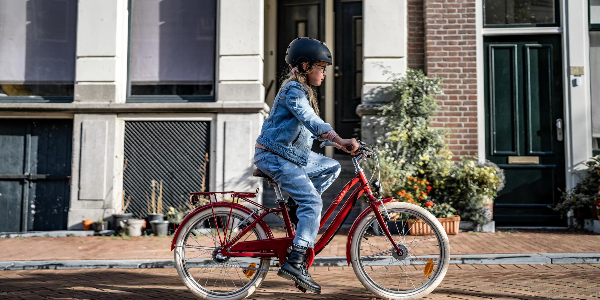 dziewczynka jadąca na rowerze miejskim w kasku rowerowym
