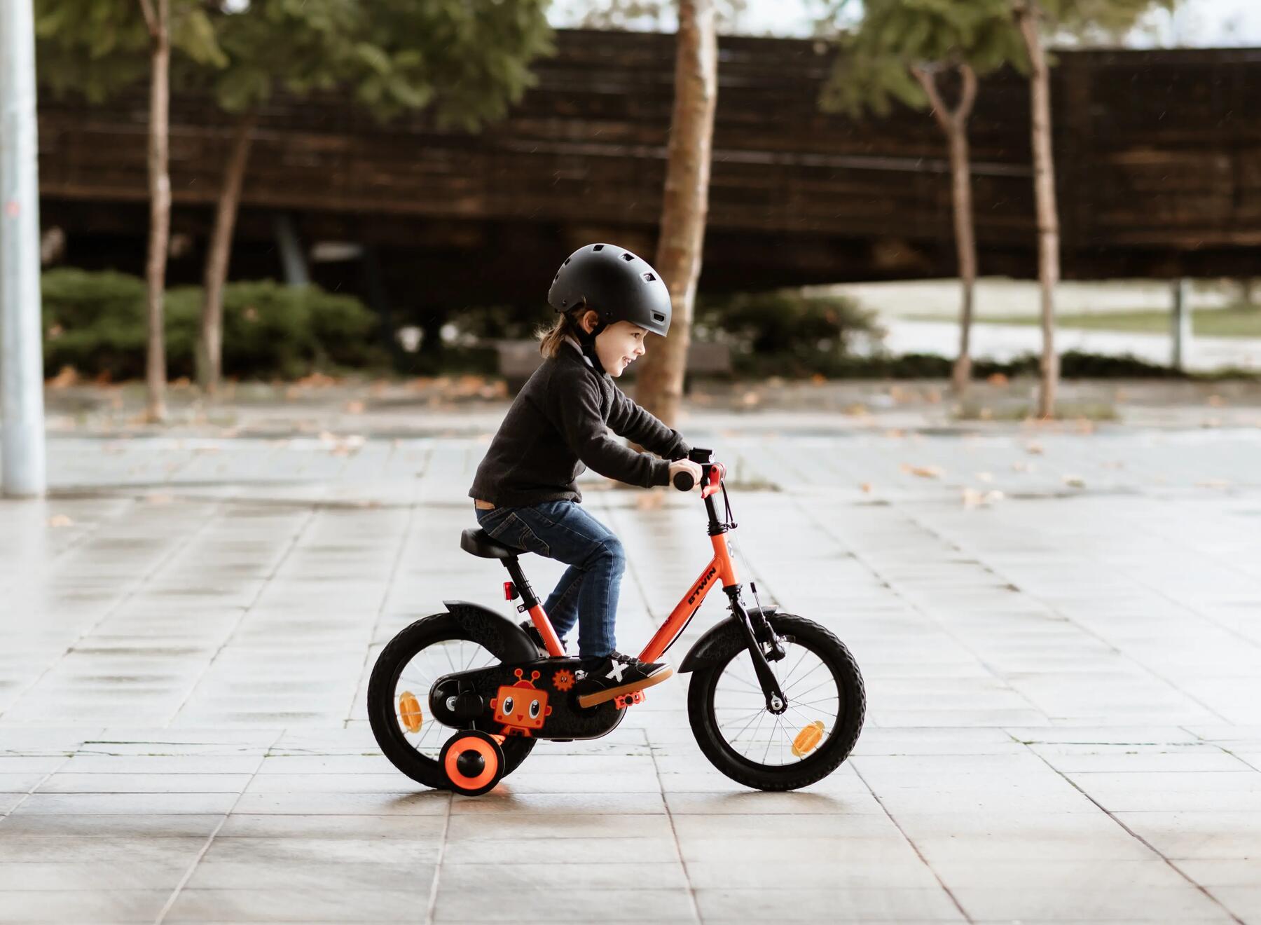 Ett barn sitter på en cykel med stödhjul