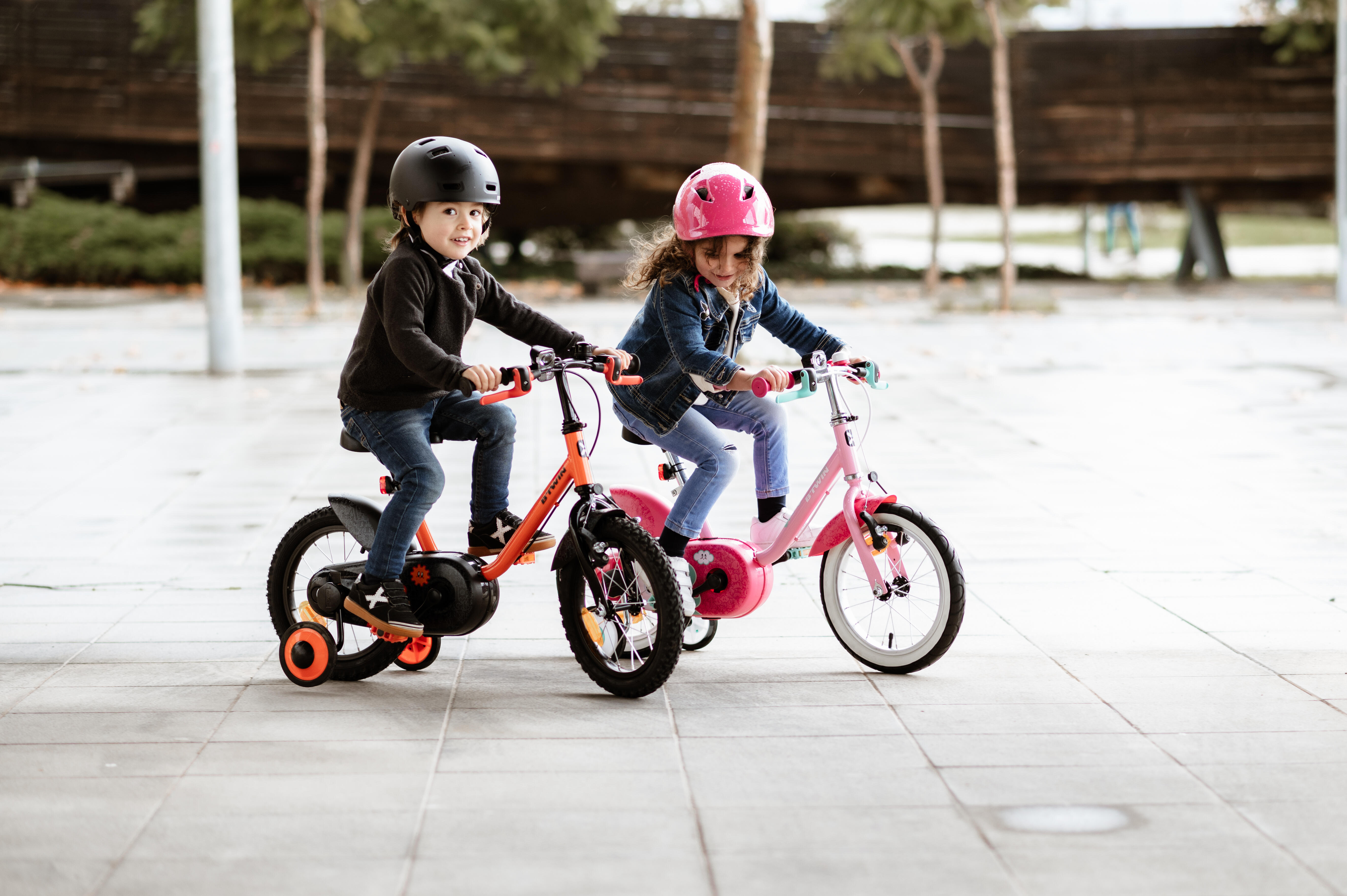 Due bambini pedalano su bici a rotelle