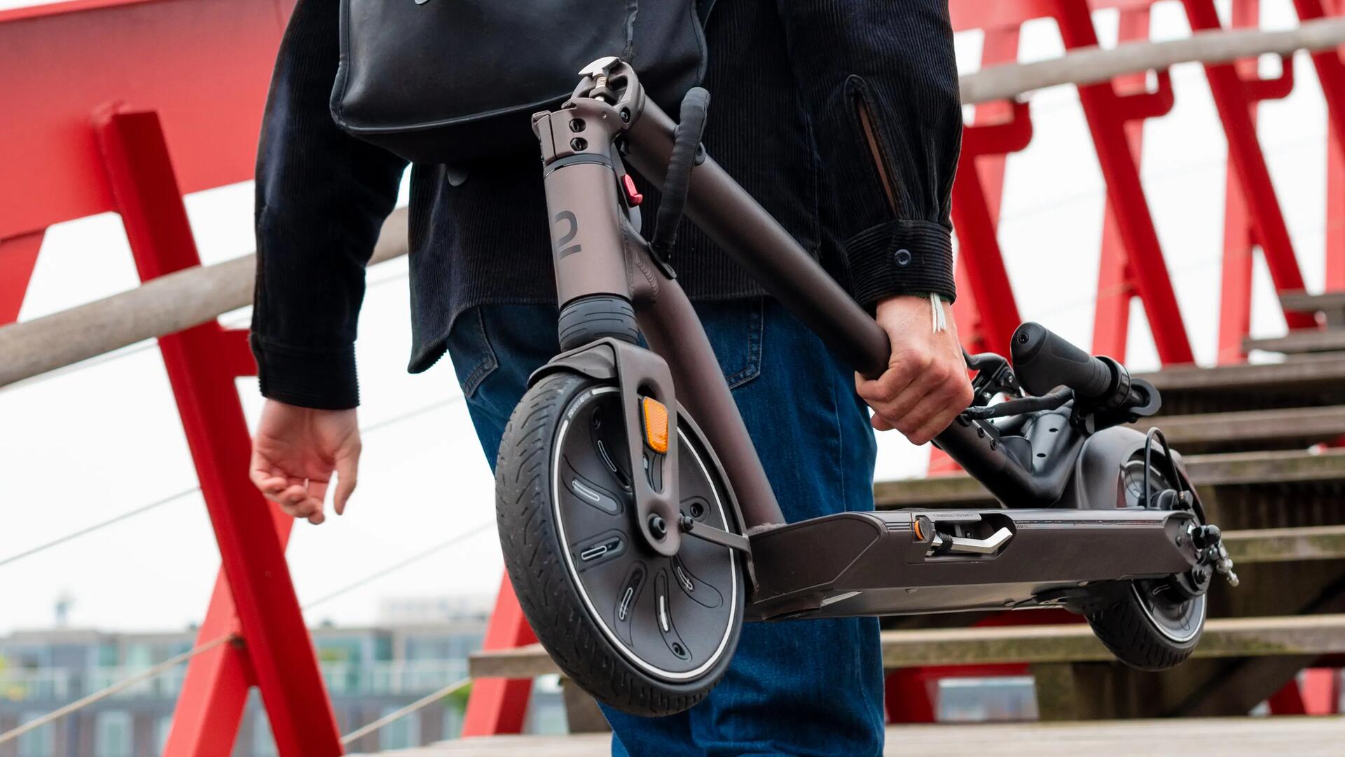 Homem a transportar trotinete elétrica dobrada na cidade