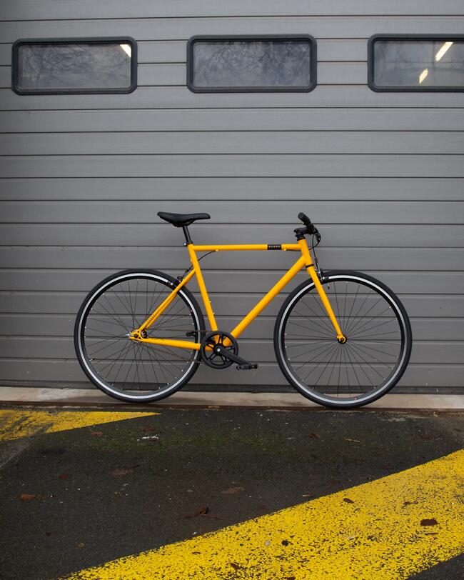 Gelbes sportliches Fahrrad vor grauem Rolltor; industrielles Ambiente