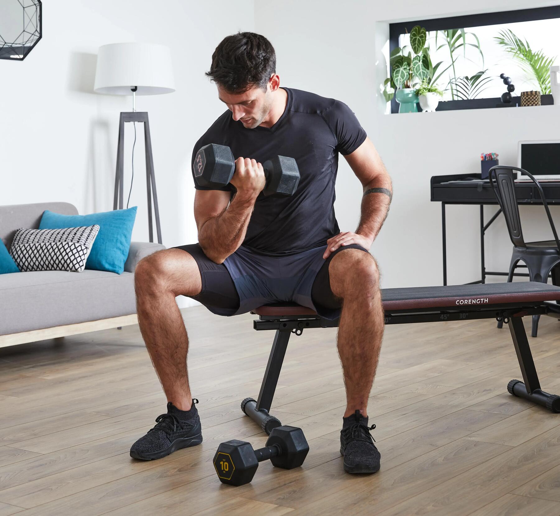 mężczyzna w odzieży fitness trenujący mięśnie rąk  z hantlami 
