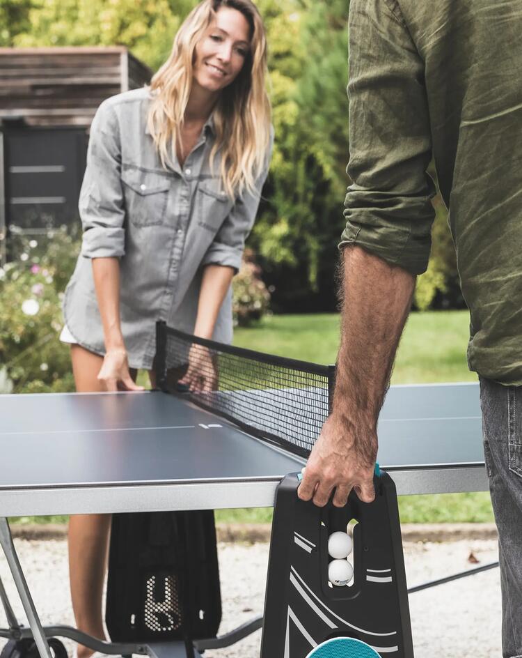 A couple adjasting a table tennis net.