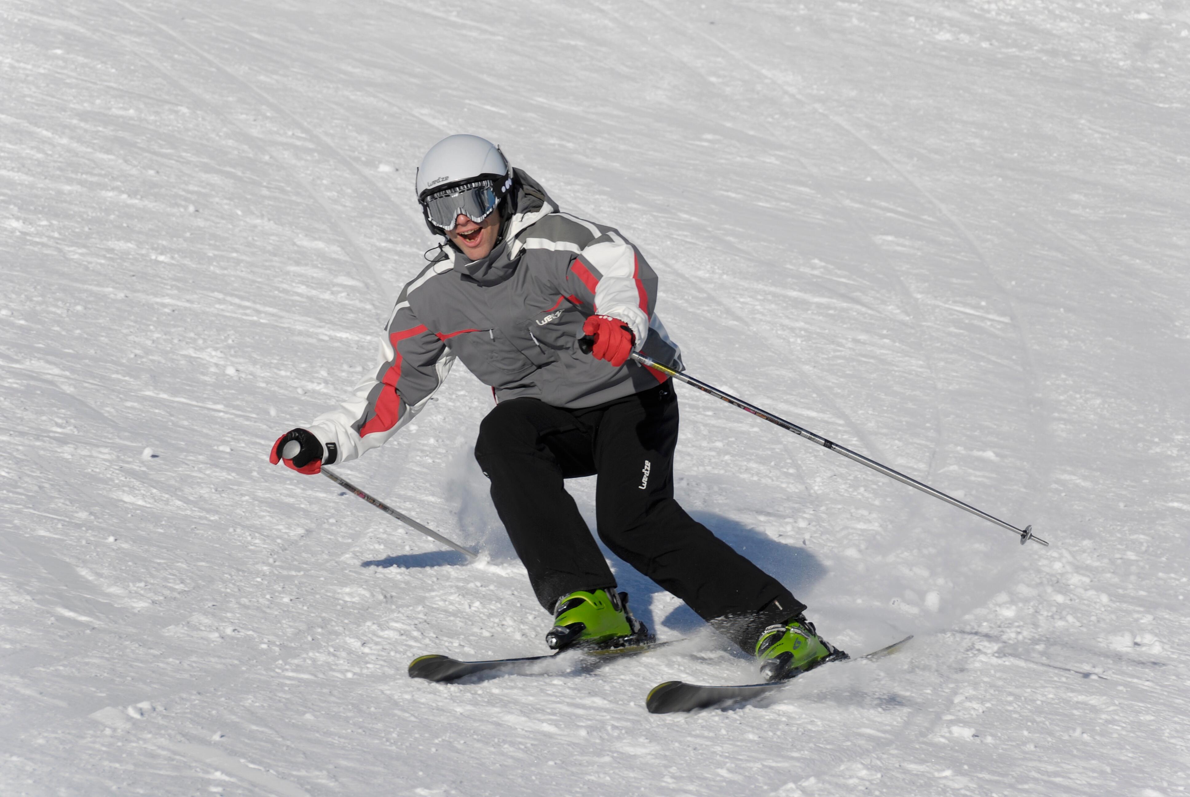 Skier wearing red ski gloves while skiing down a snowy slope