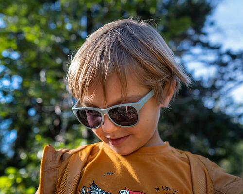 Young boy wearing sunglasses and looking down.
