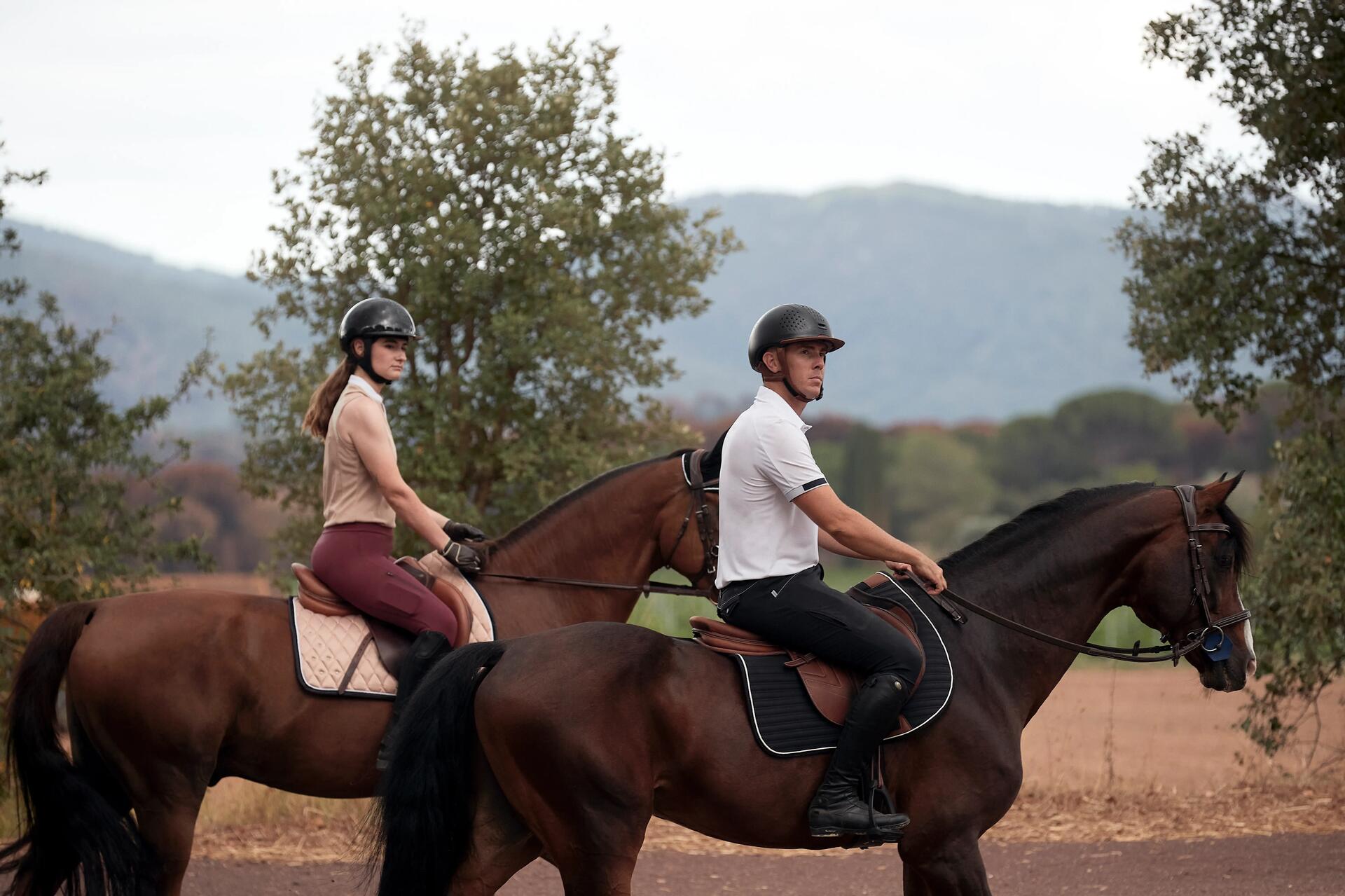 Mężczyzna i kobieta w toczkach jeździeckich chroniących podczas upadku z konia siedzący na koniach 