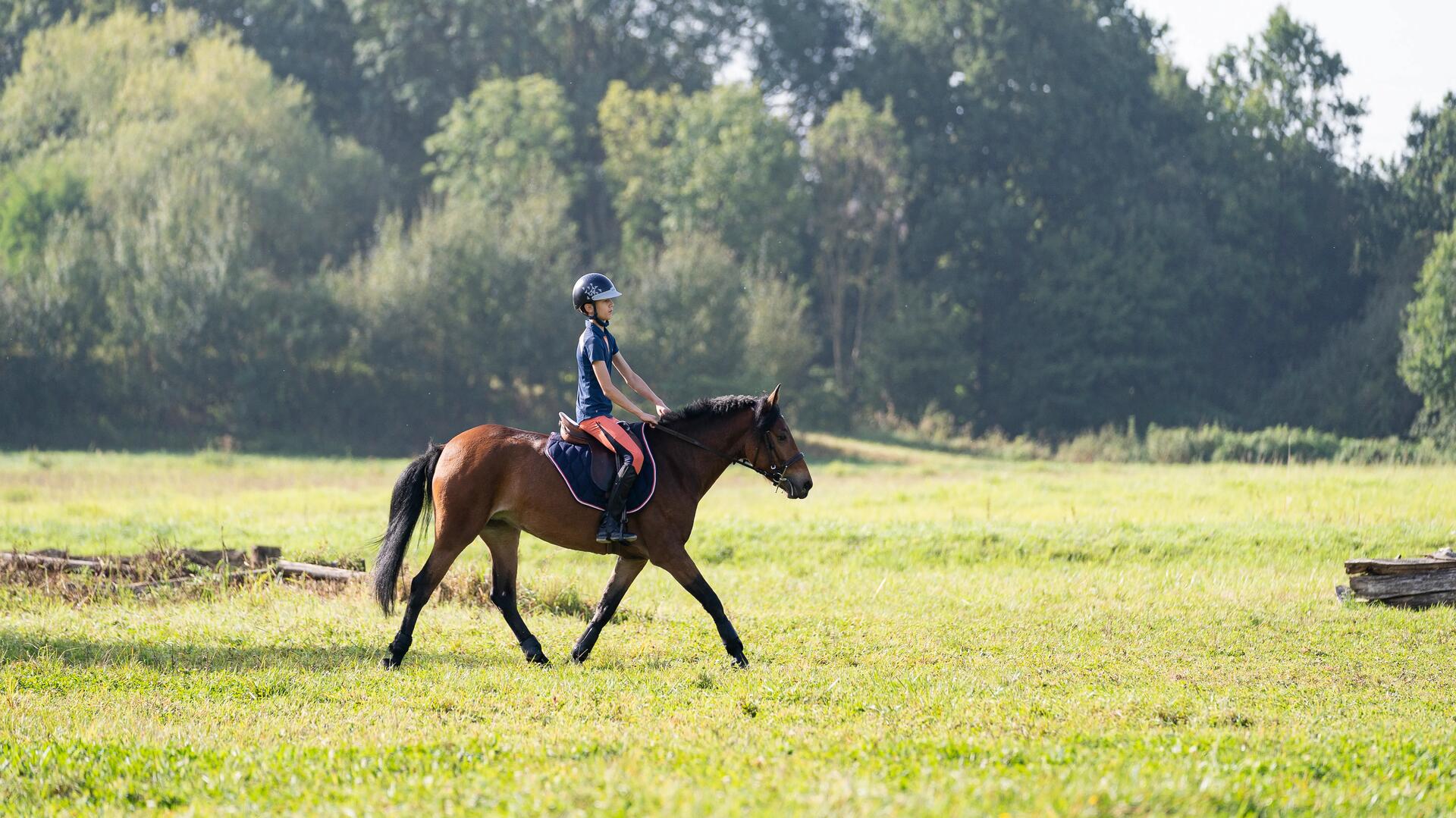 kid horseback riding in a field