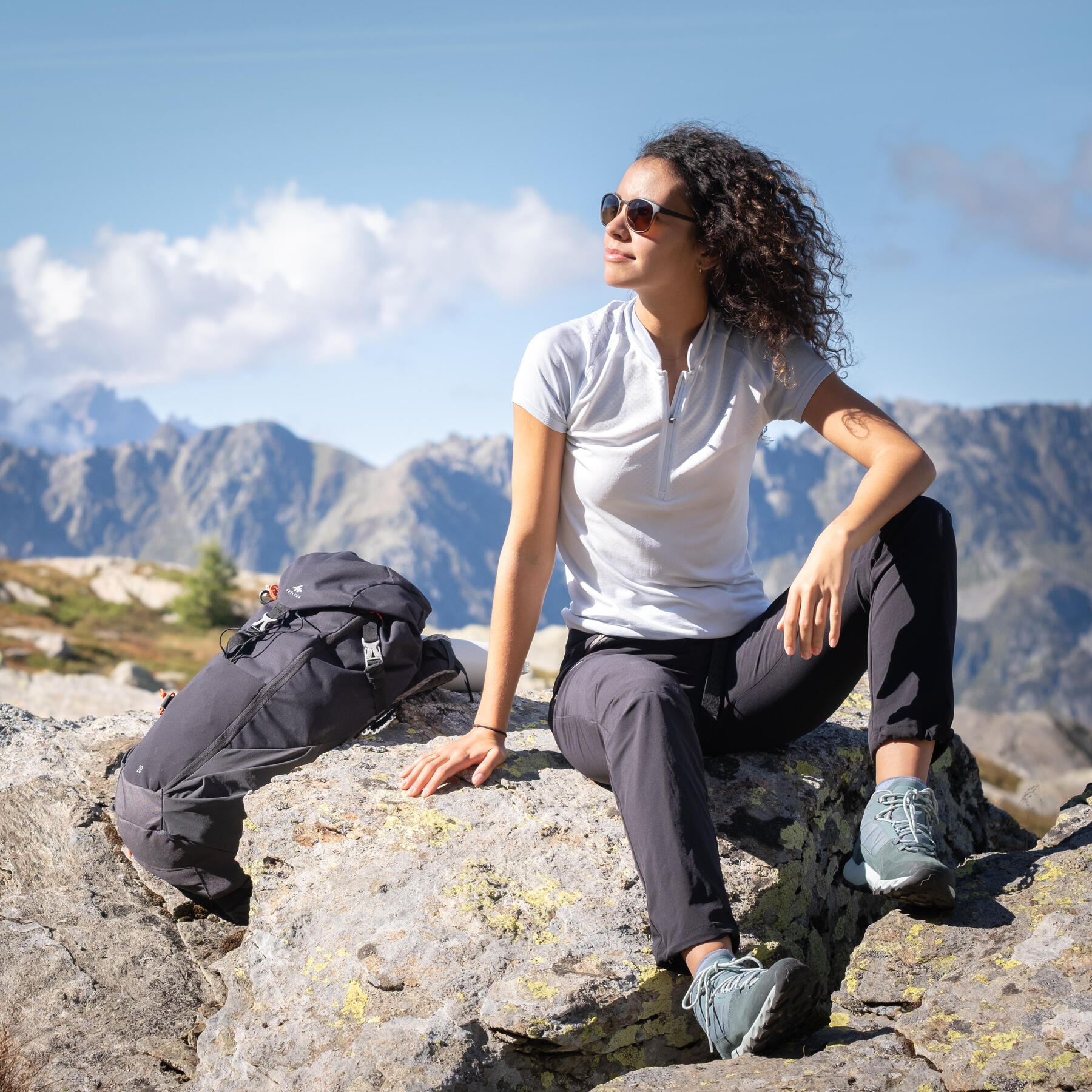 Kobieta w okularach przeciwsłonecznych siedząca latem na kamieniu w górach 