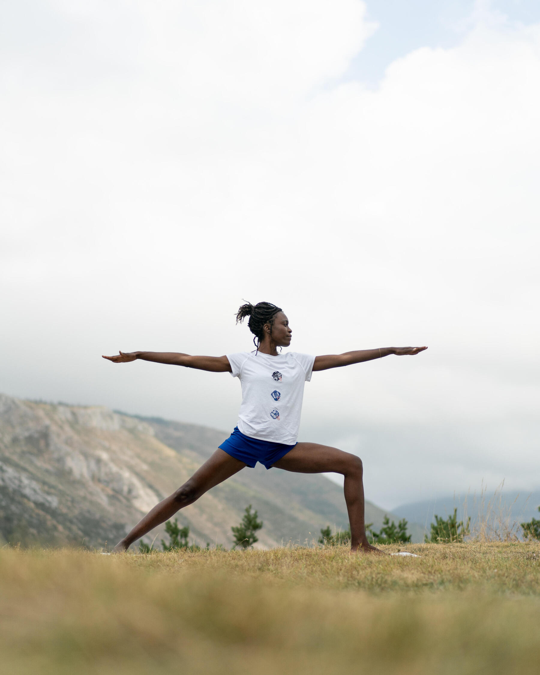 Femme en posture du guerrier dans un environnement montagneux