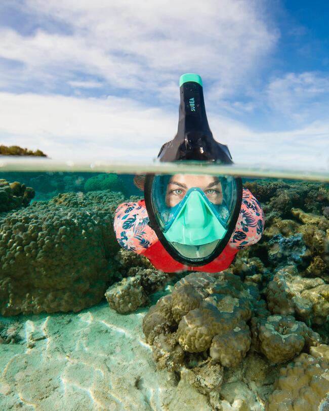 Vrouw met Easybreath snorkelmasker op zwemt tussen het rif en heeft kraakhelder zicht
