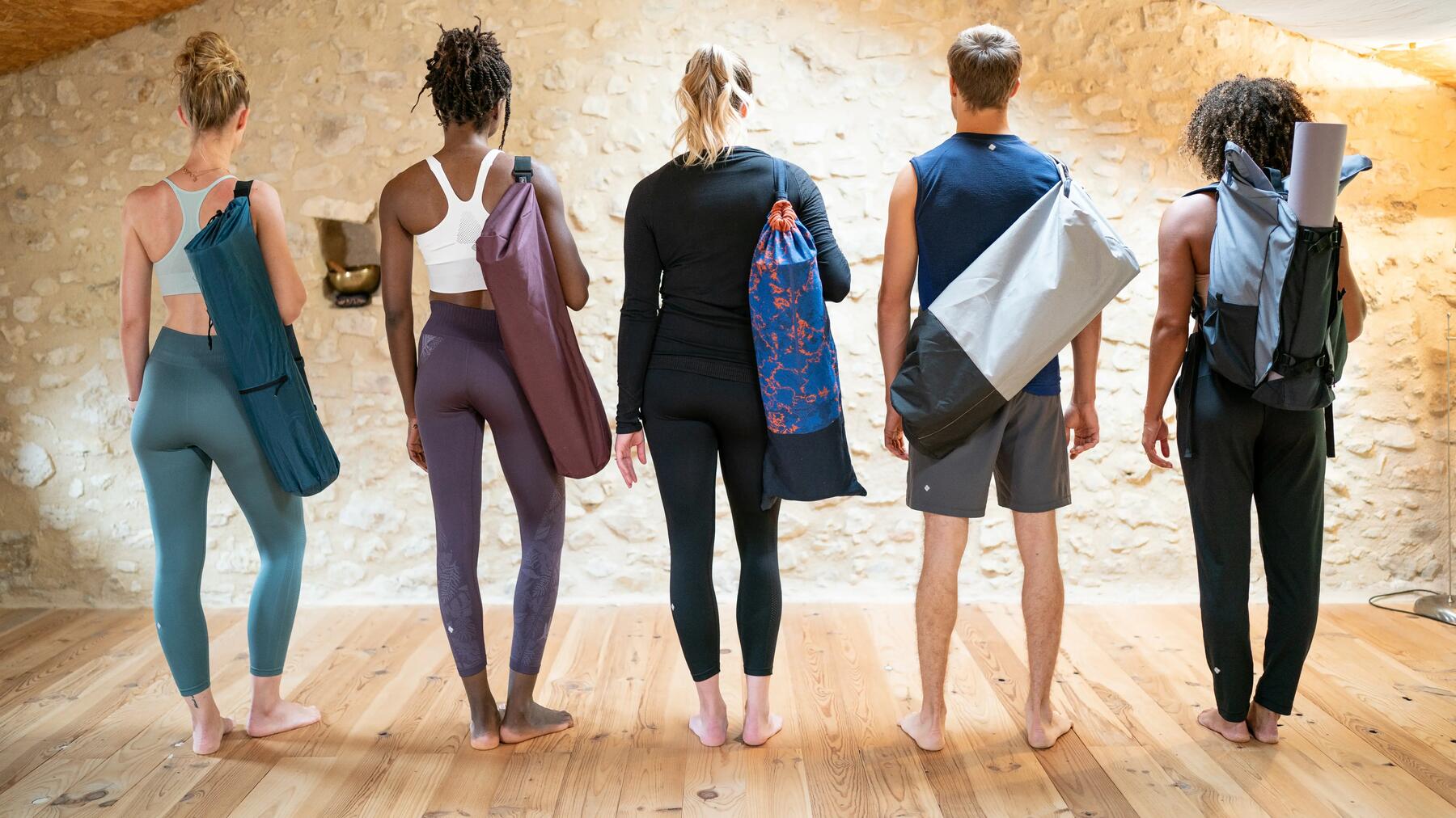Gruppe von Personen mit Yogamatten auf dem Rücken und Yogabekleidung an.