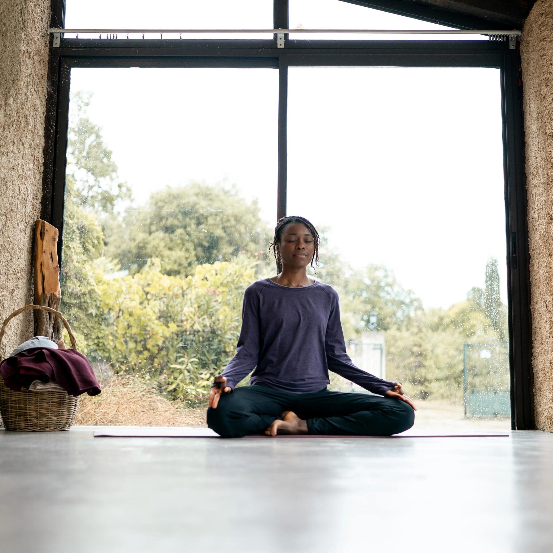 Kobieta praktykująca medytację uważności z aplikacją do medytacji na macie do jogi