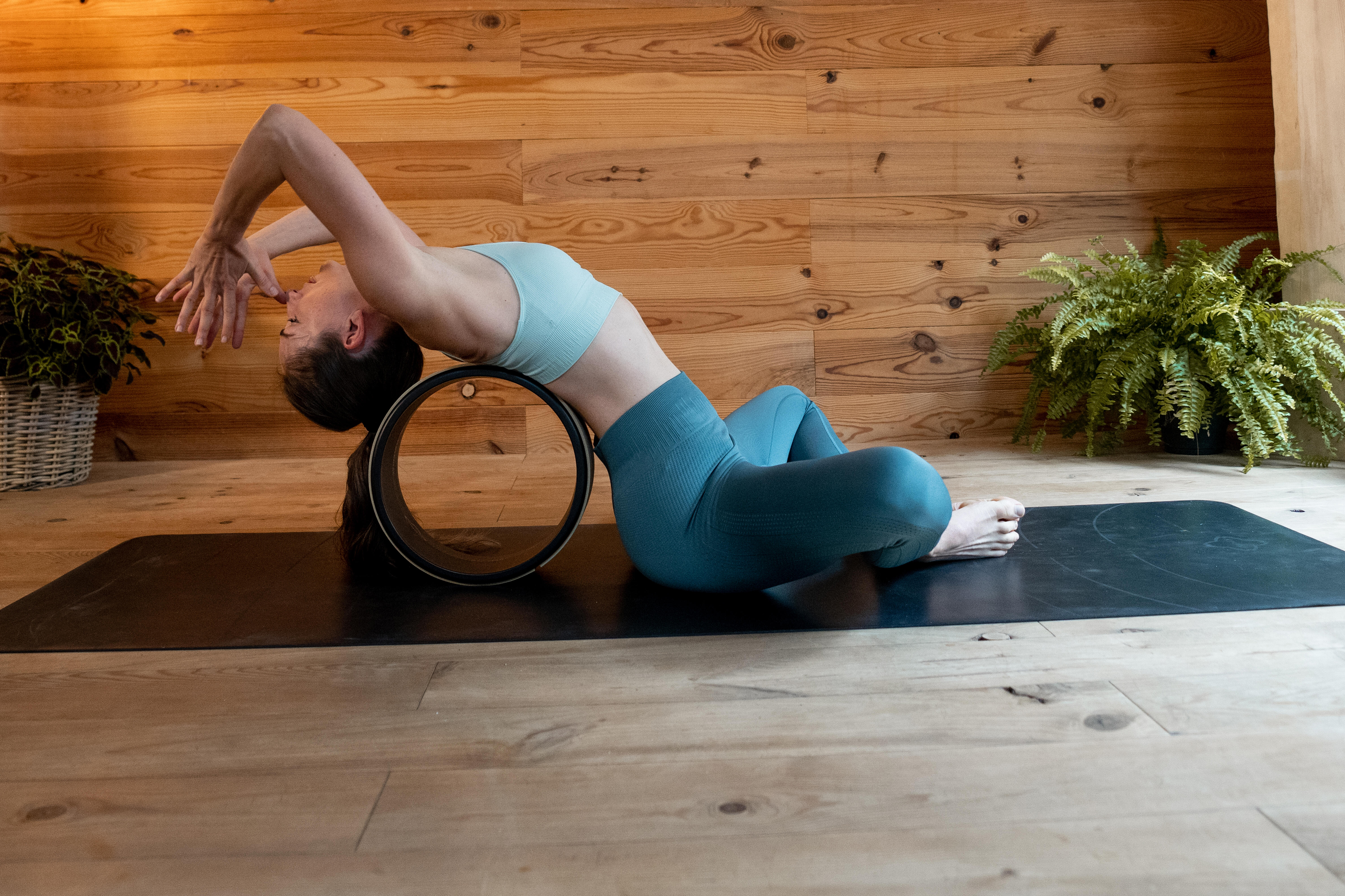 Woman using a yoga wheel for support during a backbend on a yoga mat