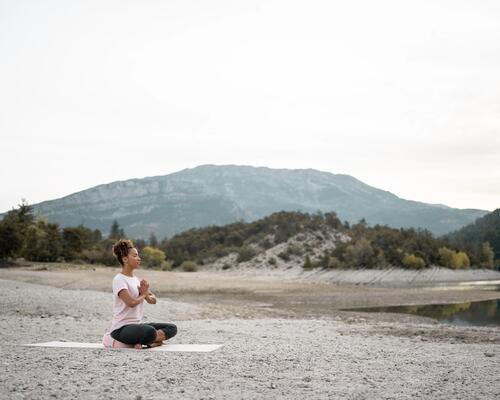 Kobieta siedząca na poduszce uprawiająca medytację Zen w plenerze
