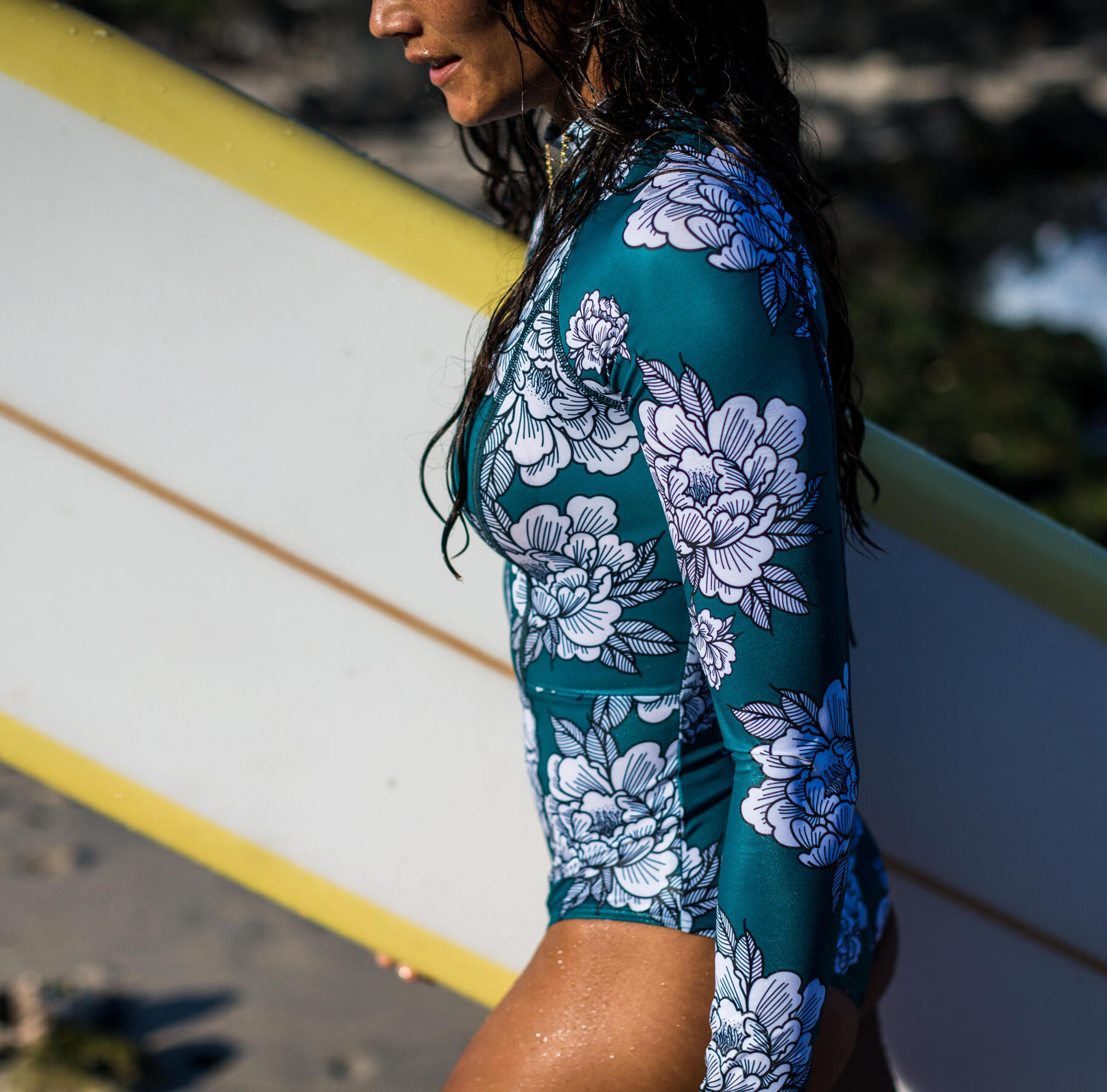 woman with here surf board under the arm walking on a beach