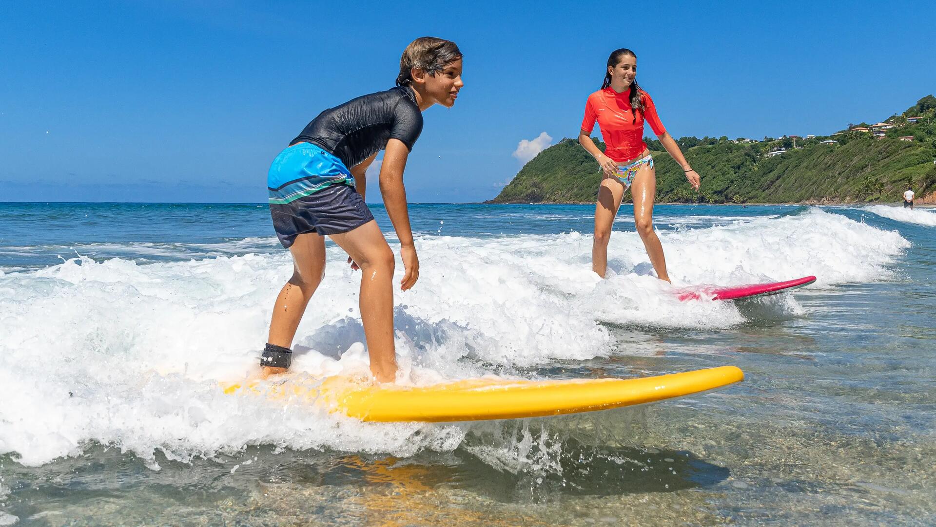 chłopak i dziewczyna  w odzieży z filtrem UV pływający na deskach surfingowych