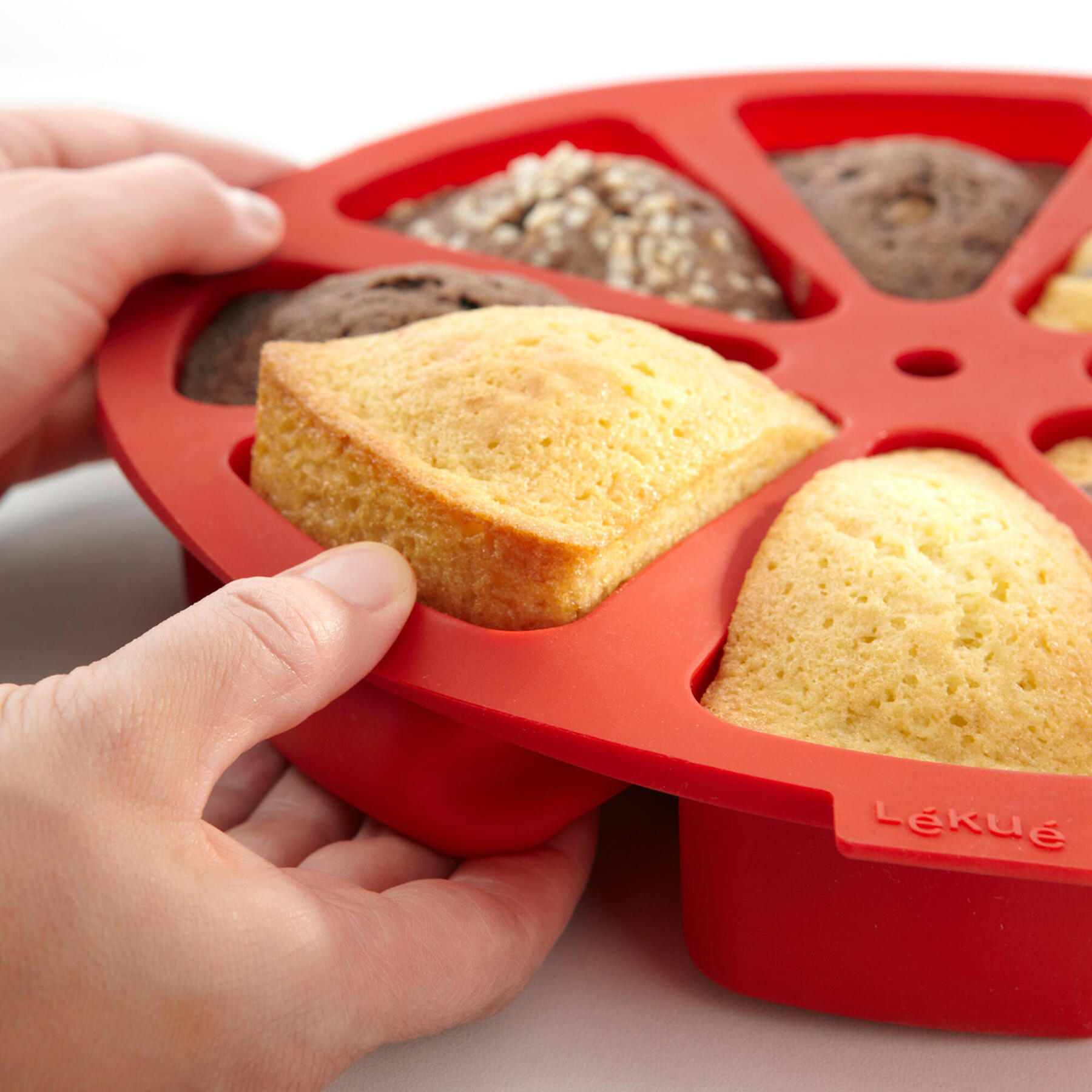 Schoko- und Vanille Muffins werden aus roter Silikonform befreit.