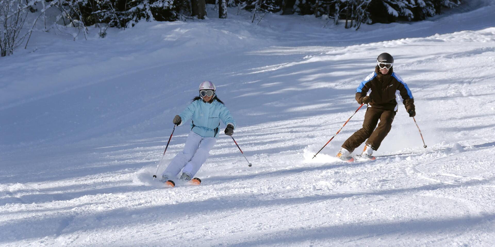 Two advanced skiers making their way down a slope