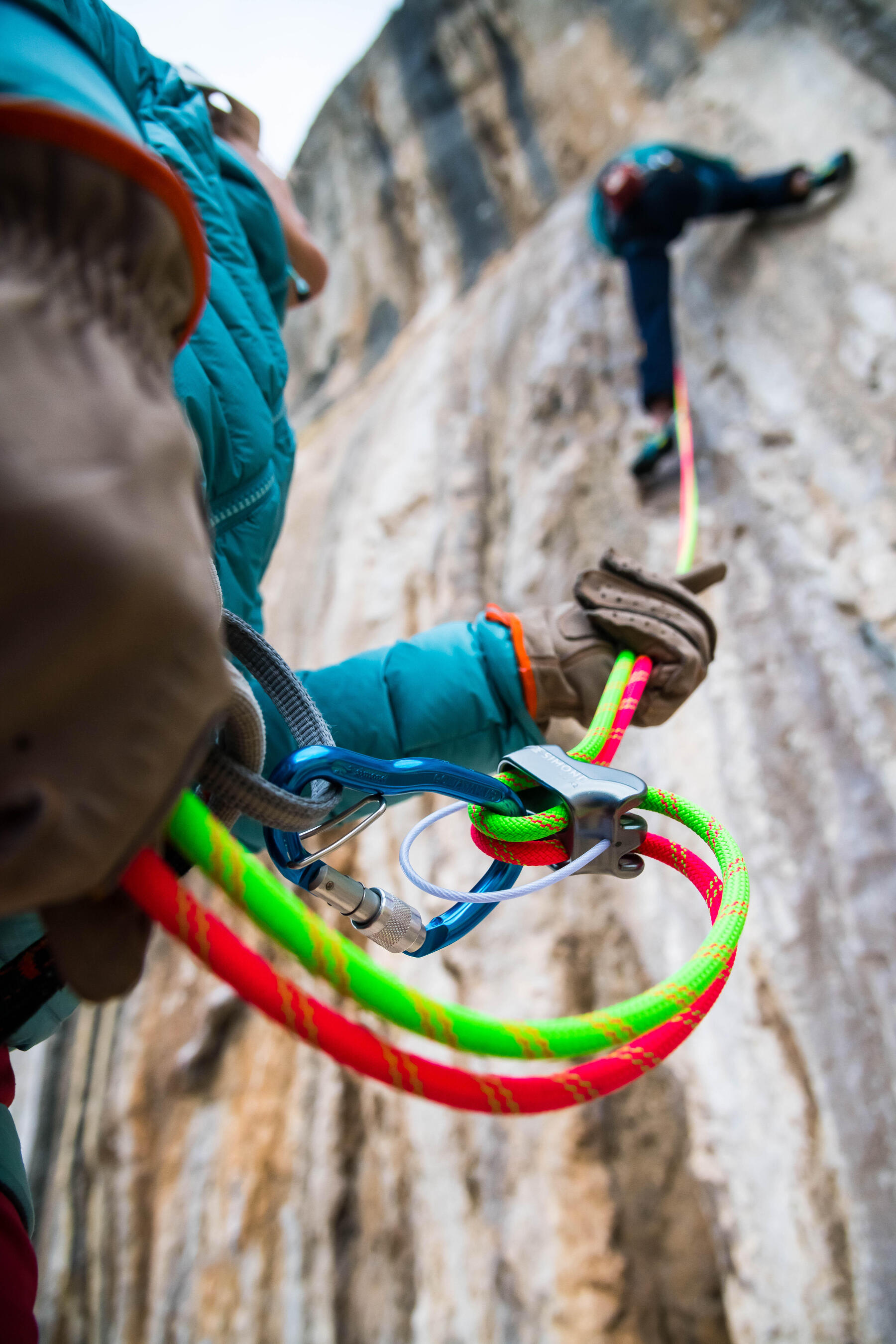 Eine Person hält zur Sicherung ein Seil mit Kletterknoten im Karabiner