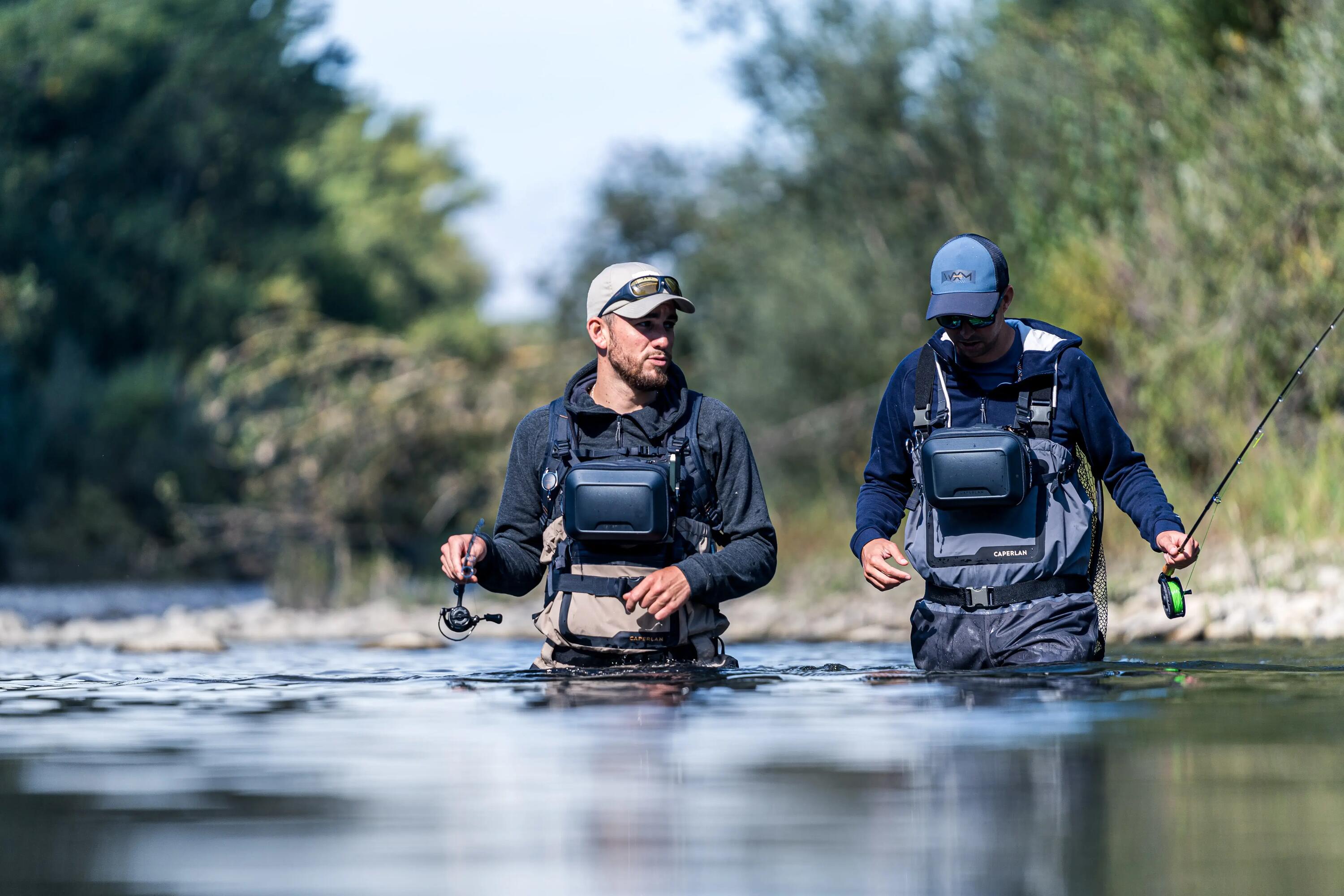 Zwei Angler in Wathose laufen zum Wasser