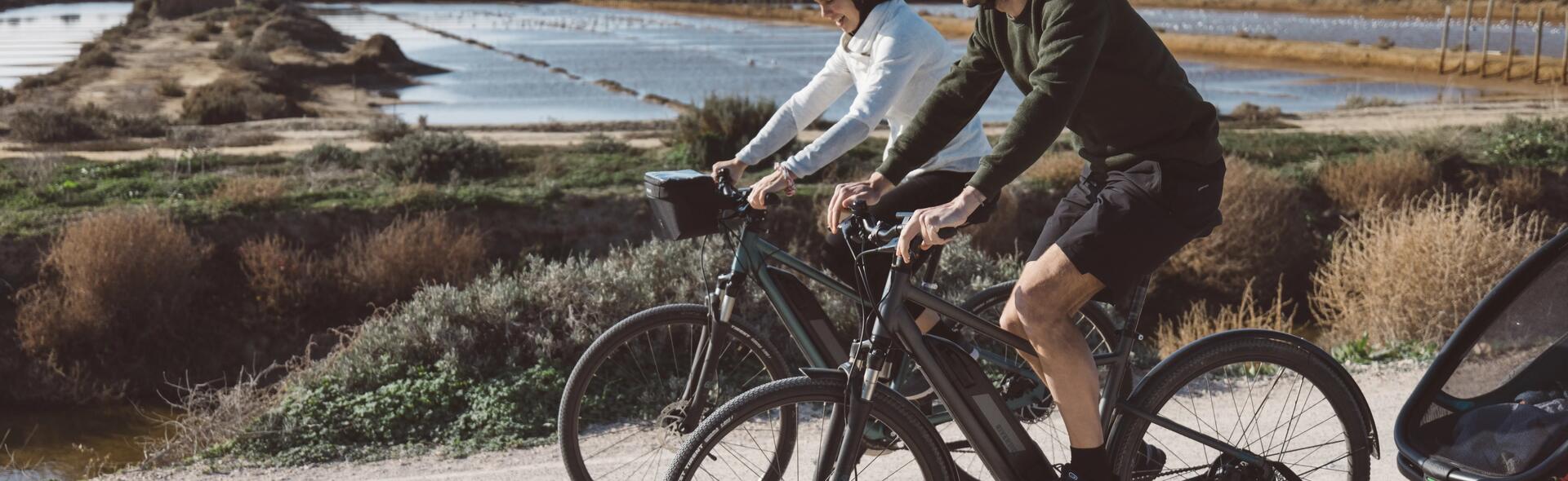 kobieta i mężczyzna jadący na rowerach elektrycznych w kaskach