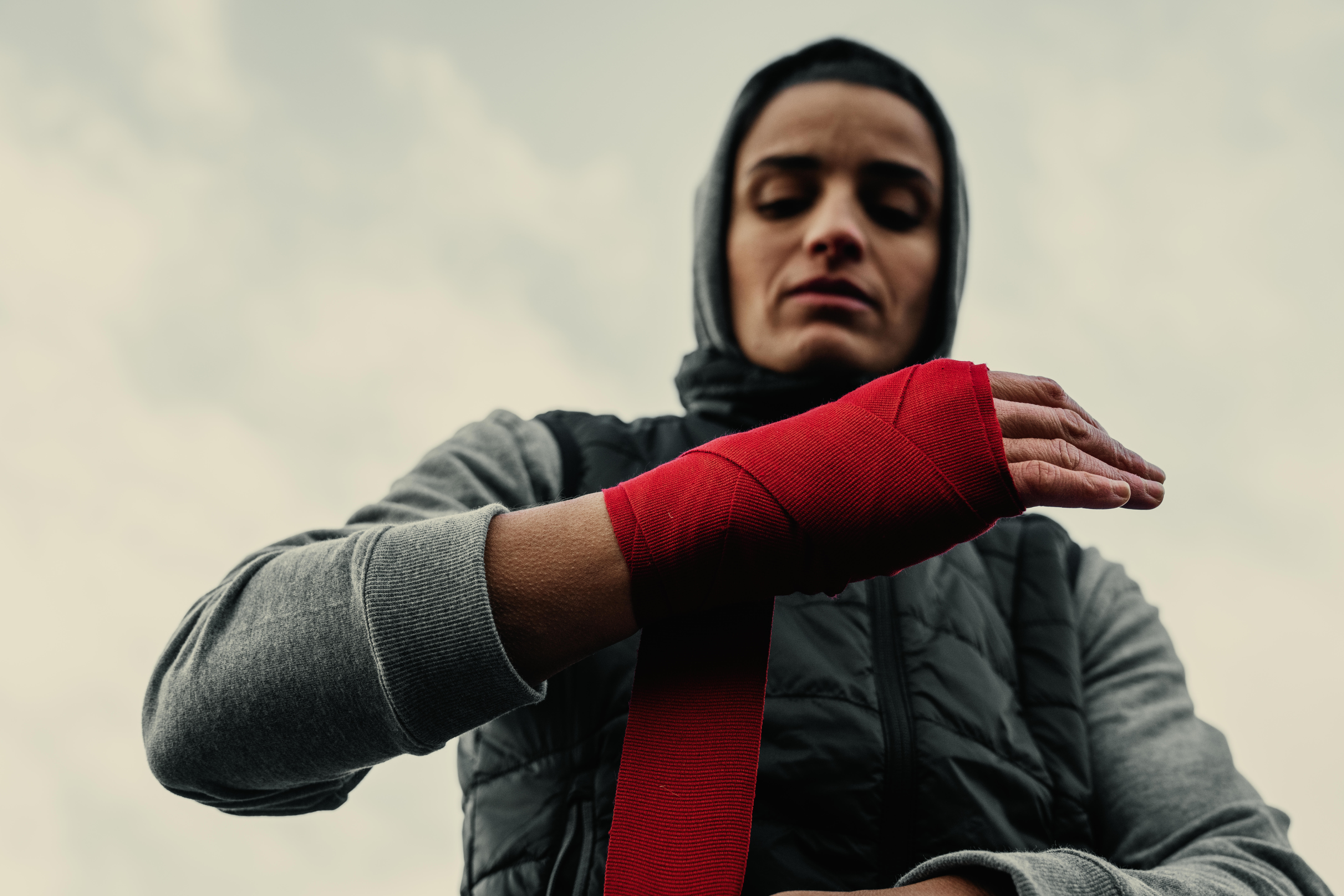Boxer wrapping a hand with red boxing hand wraps before training