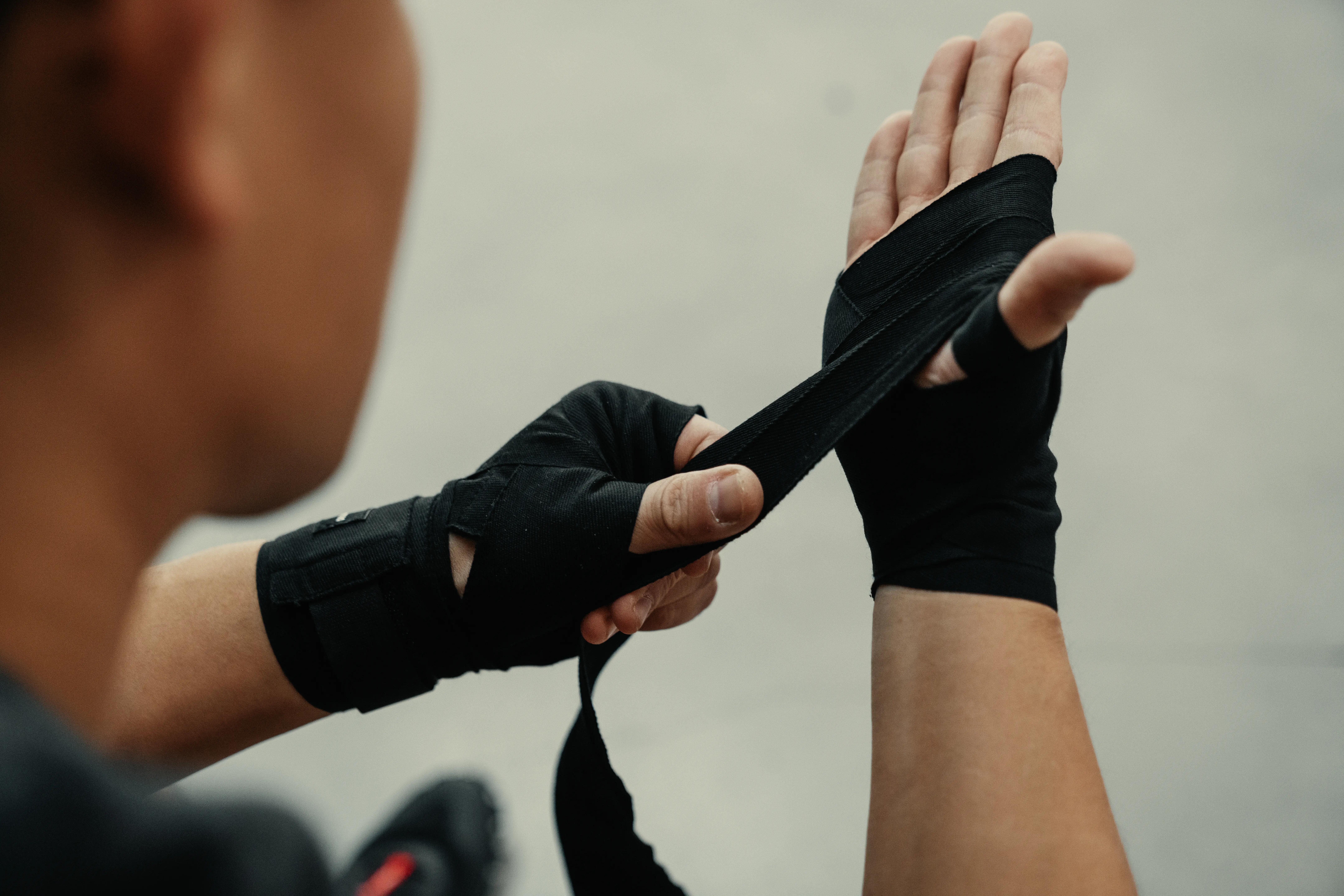 Close-up of boxer wrapping a hand with black boxing hand wraps